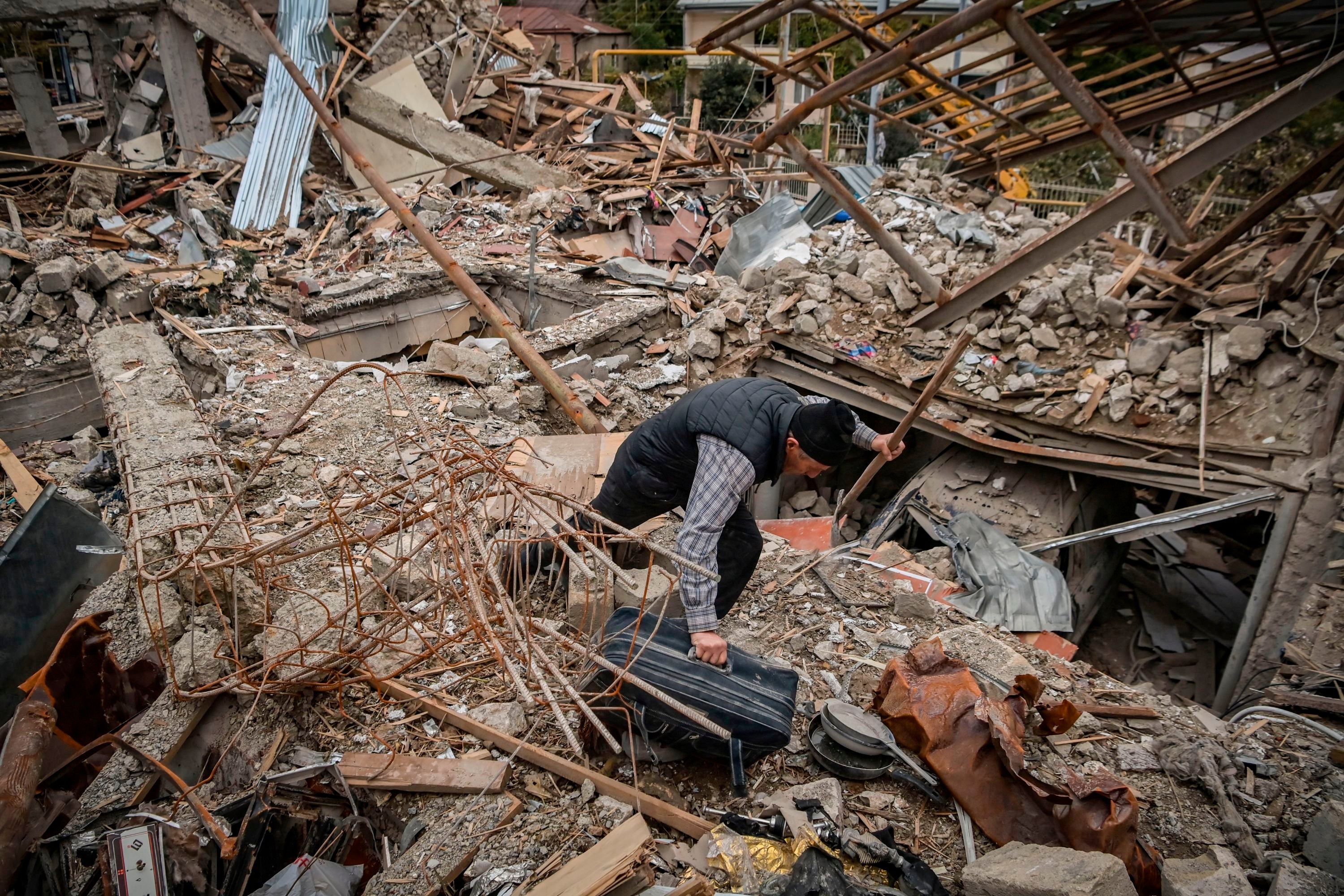 Oficial de policía busca sus pertenencias en los restos de su casa, que se dice fue destruida por el bombardeo azerí