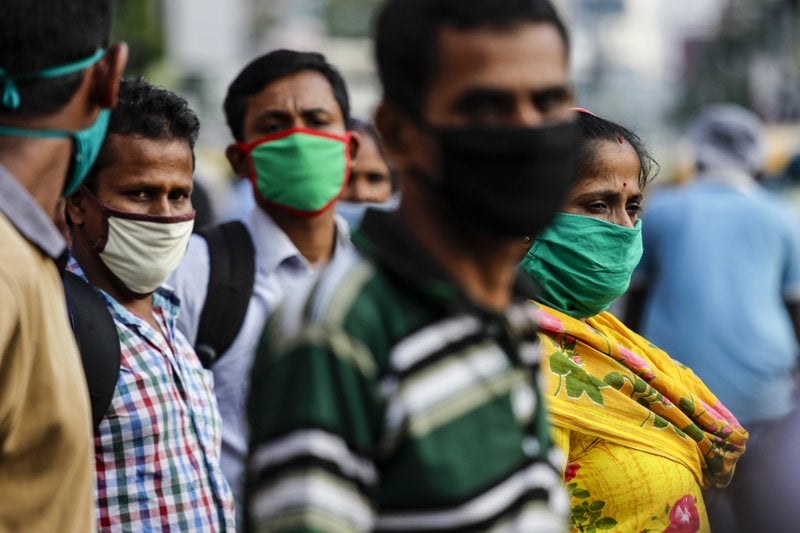Pasajeros con mascarillas como precaución contra el coronavirus esperan a un autobús en Kolkata, India, el sábado 10 de octubre de 2020. (AP Foto/Bikas Das)