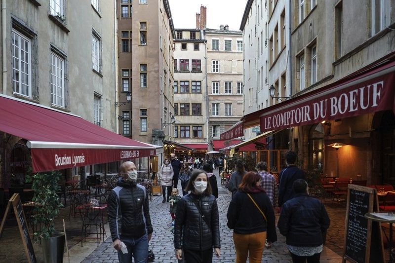 Personas con mascarilla pasan frente a restaurantes en el centro de Lyon, Francia, el sábado 10 de octubre de 2020. (AP Foto/Laurent Cipriani)