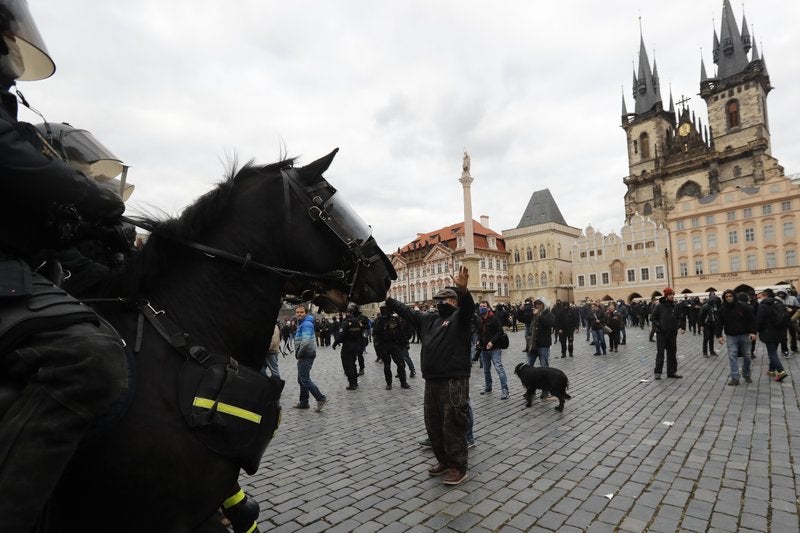 Policías a caballo enfrentan a personas que protestan contra las nuevas restricciones para frenar los caso de coronavirus