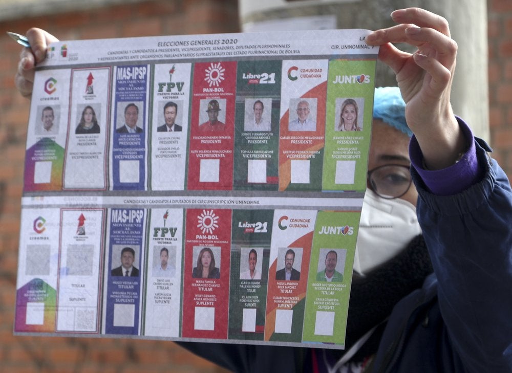 Un funcionario electoral muestra las papeletas a un votante en un colegio electoral durante las elecciones generales en La Paz, Bolivia, el domingo 18 de octubre de 2020. (Foto AP/Martín Mejía)
