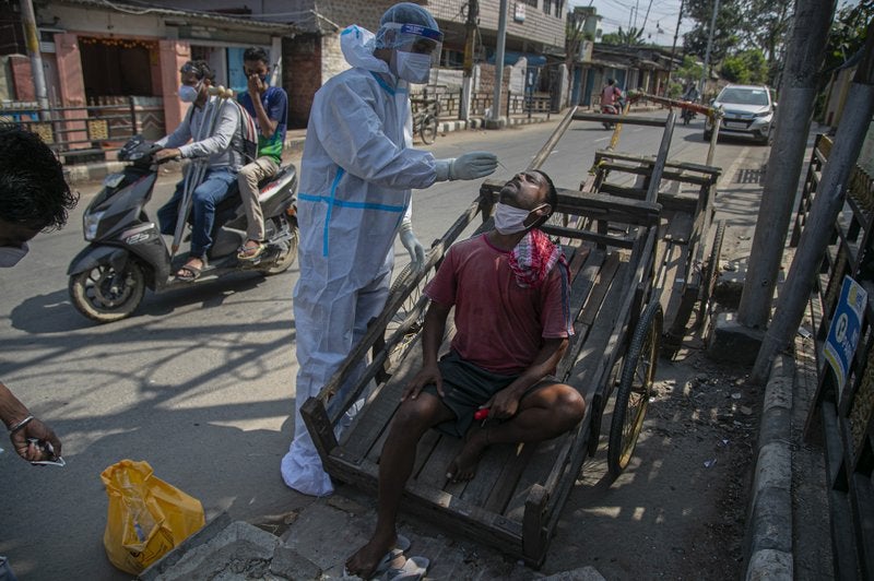 Un trabajador de la salud toma una muestra nasal de un tirador de carretillas durante pruebas al azar de COVID-19 en un mercado en Gauhati