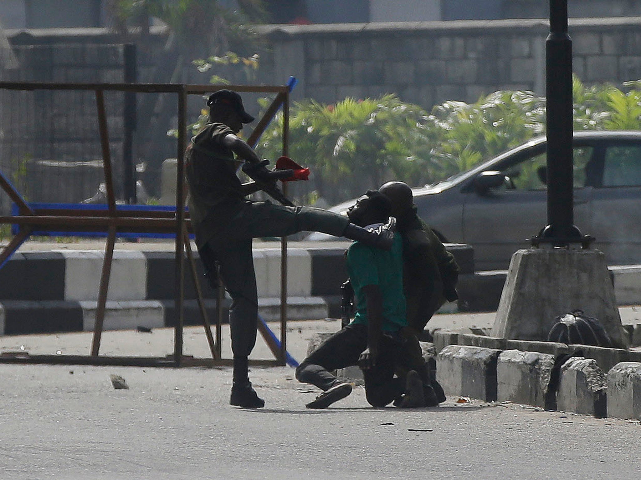 Un oficial de policía patea a un manifestante detenido por la puerta de peaje de Lekki en Lagos.