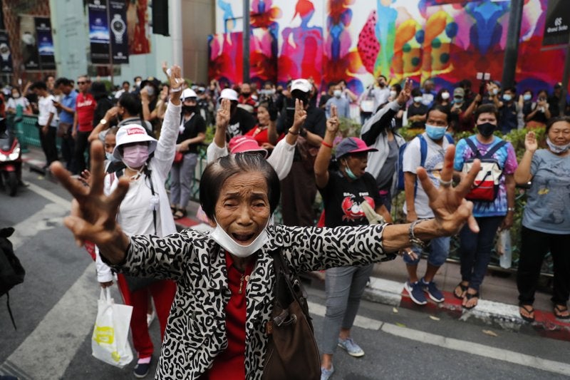 Manifestantes prodemocracia alzan tres dedos en alusión a sus reclamaciones cerca de una zona comercial en Bangkok, Tailandia