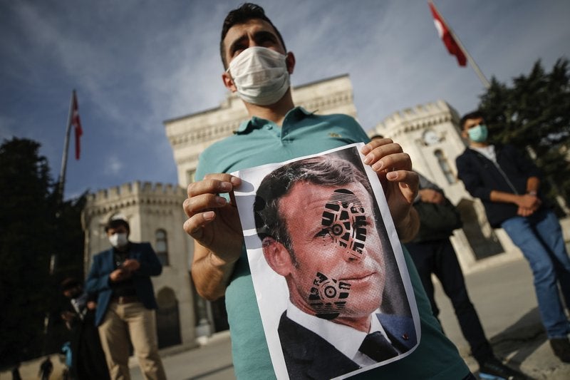 Un joven sostiene una fotografía del presidente francés con una huella de zapato en el rostro durante una protesta contra Francia, en Estambul.