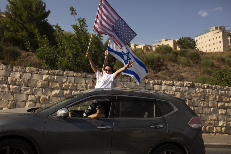 Simpatizantes del presidente de Estados Unidos Donald Trump ondean una bandera estadounidense y una israelí.
