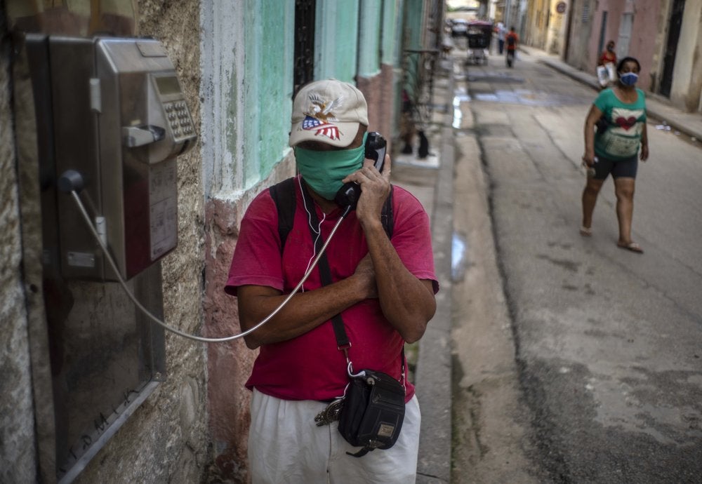 Con una mascarilla protectora en medio de la pandemia del nuevo coronavirus, un hombre habla por un teléfono público en La Habana Vieja, Cuba, el lunes 26 de octubre de 2020. (Foto/Ramón Espinosa)