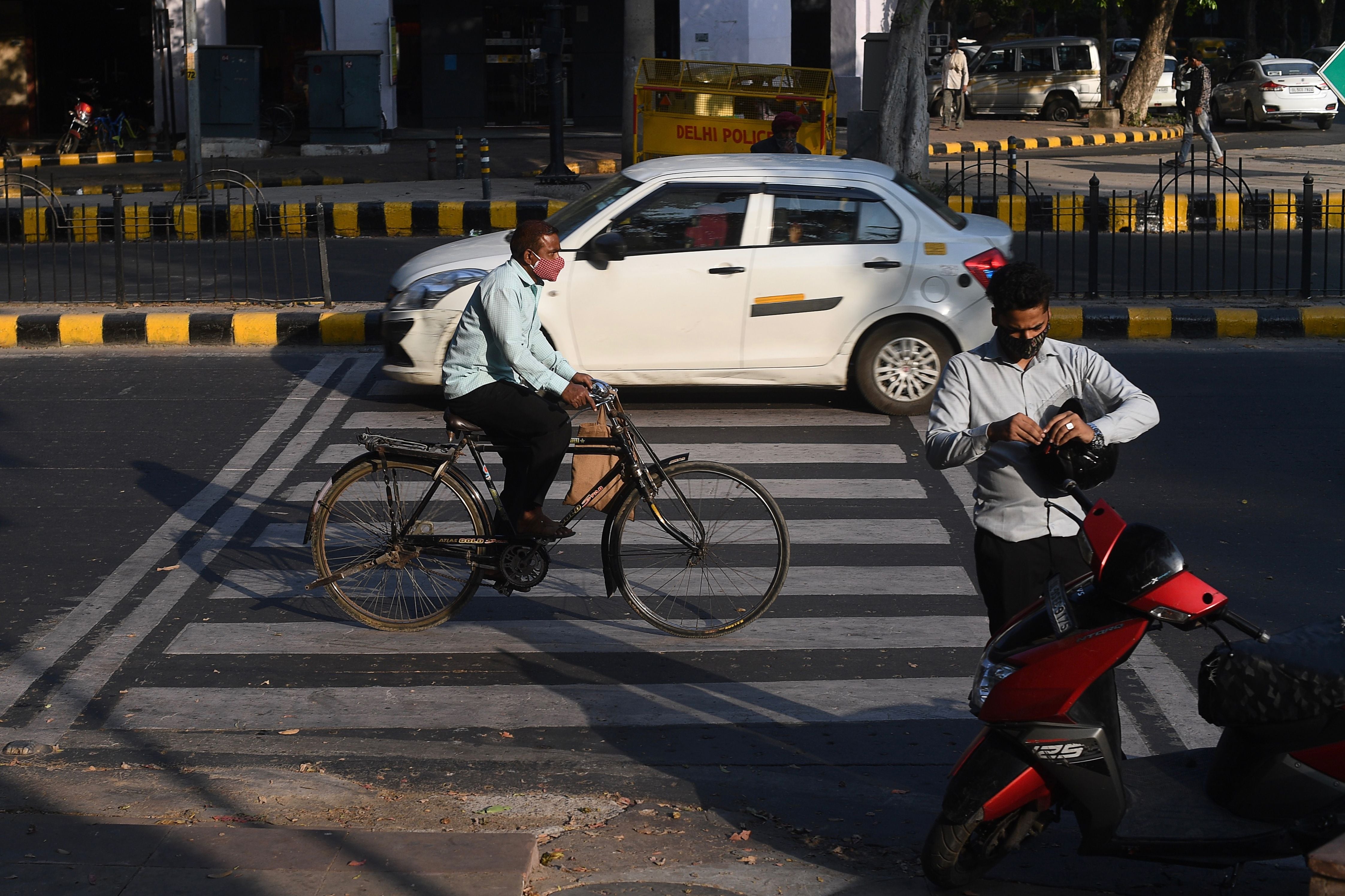 Peatones con mascarillas como medida preventiva contra el COVID-19 caminan por una carretera en Nueva Delhi.