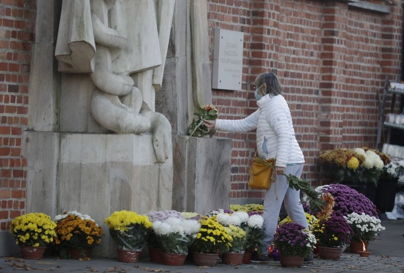 Flores y veladoras que la gente ha colocado frente a las puertas del cementerio Powazki después que el gobierno polaco cerrara todos los panteones.
