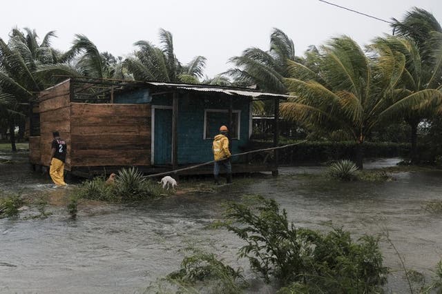 Dos hombres caminan por los perímetros de una casa rodeados por las inundaciones provocadas por el huracán Eta en Wawa.
