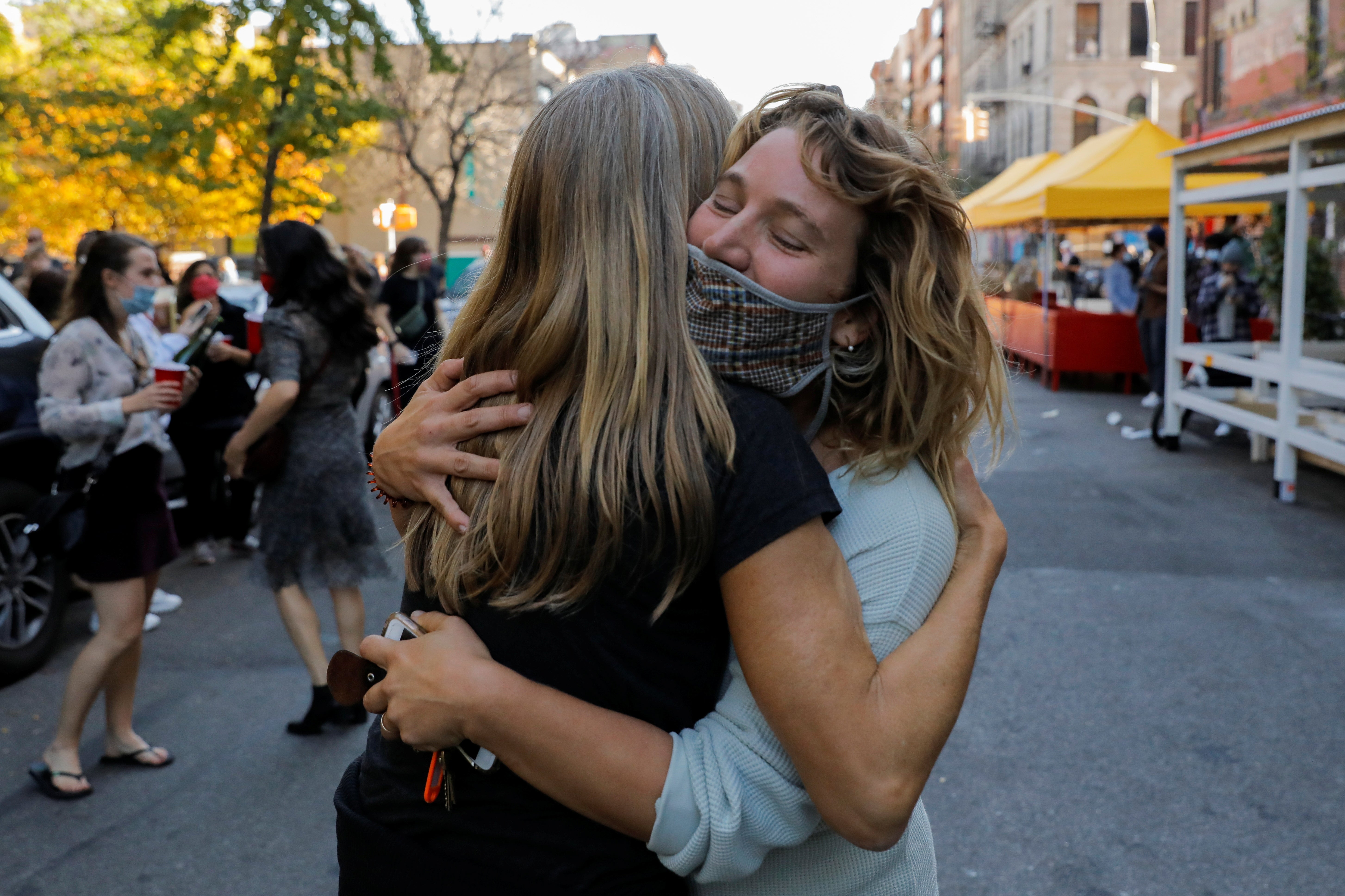 La gente se abraza mientras celebran en el barrio Alphabet City de Manhattan