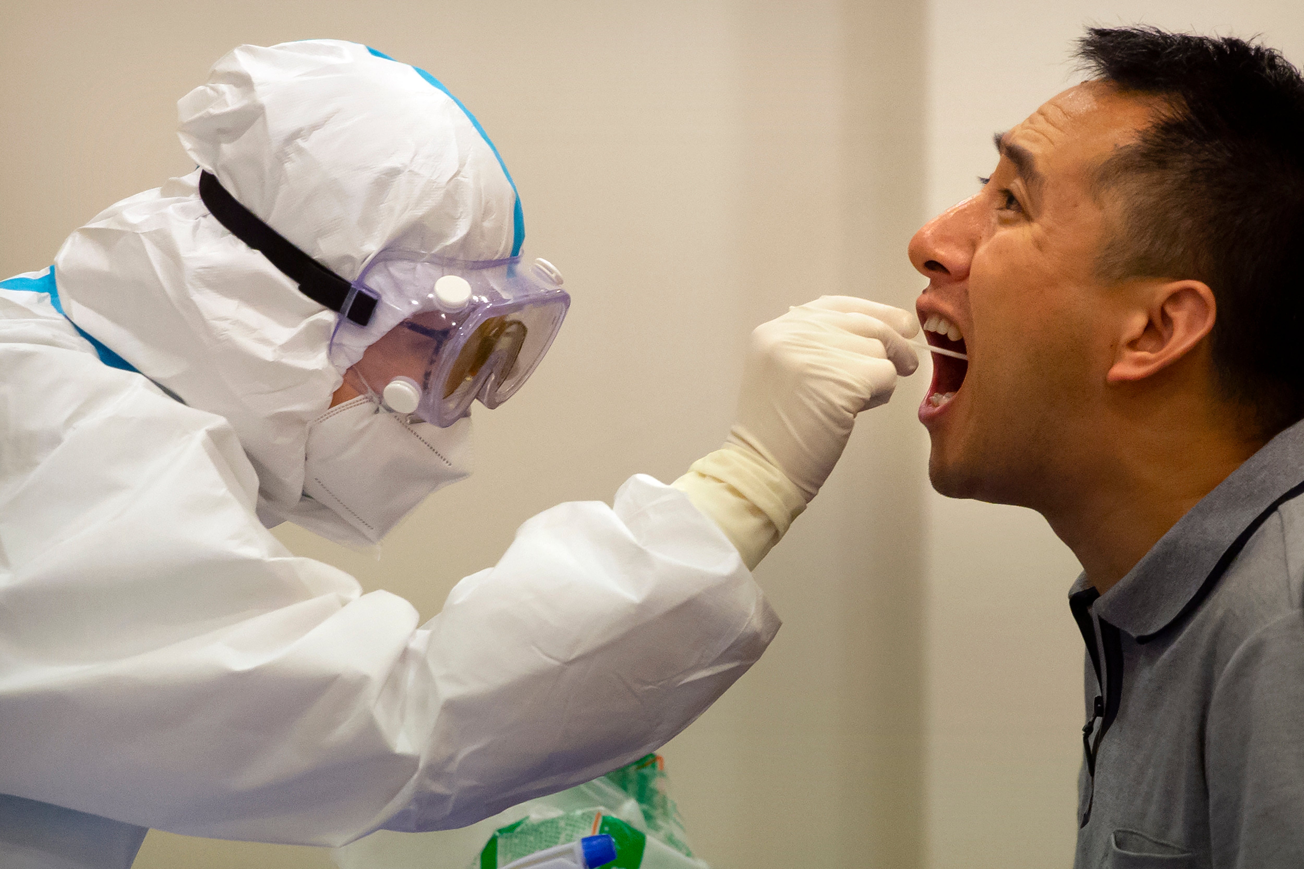 Personal médico le realiza una prueba de coronavirus a un hombre en Hainan, China, el 22 de noviembre de 2020.
