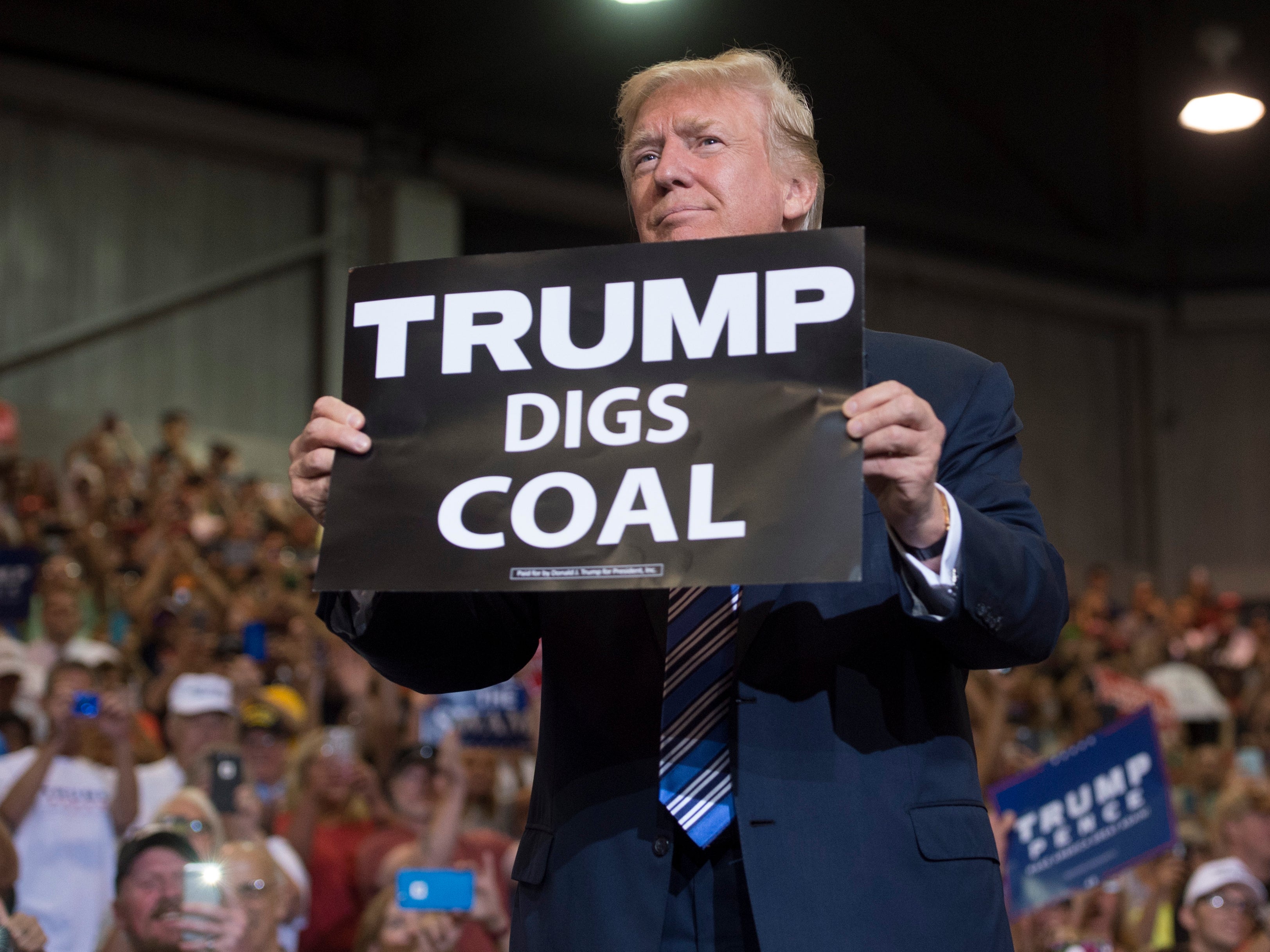 Donald Trump sostiene un cartel de “Trump excava carbón” cuando llega a un mitin en Virginia Occidental en agosto de 2017