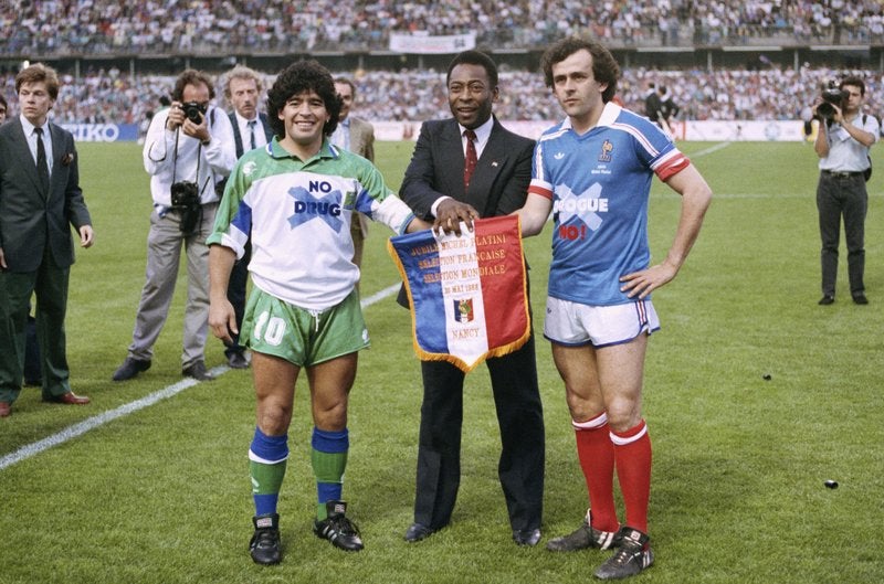 En imagen de archivo del 23 de mayo de 1998, el astro argentino Diego Armando Maradona, izquierda, el brasileño Pelé, centro, y el francés Michel Platini posan estrechando manos durante el partido de despedida de Platini en el estadio Nancy, en el este de Francia.