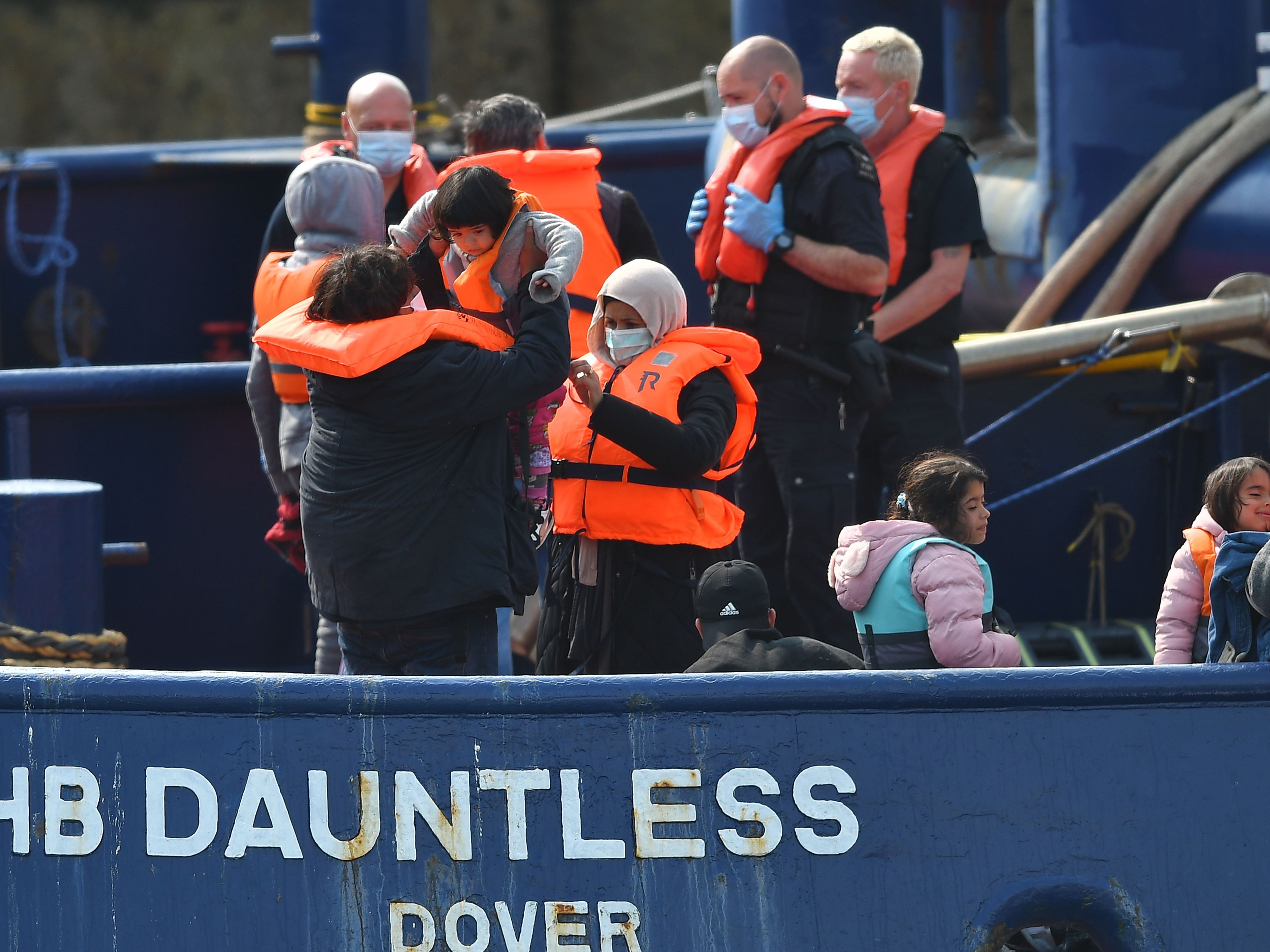 Waleed, de 29 años, un migrante kuwaití, sube a un niño a bordo del remolcador DHB Dauntless cuando la Fuerza Fronteriza del Reino Unido lo lleva a la costa después de cruzar ilegalmente el Canal de la Mancha desde Francia en un bote el 11 de septiembre de 2020.