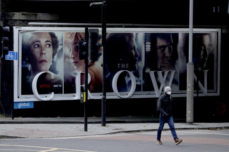 En esta fotografía del viernes 20 de noviembre de 2020, un hombre pasa frente a un anuncio de la serie de Netflix “The Crown” en Londres.