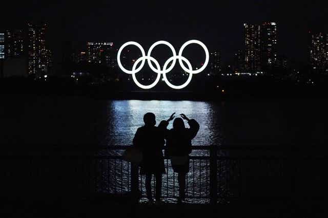 Una pareja observan los anillos olímpicos flotando en el distrito de Odaiba de Tokio, el martes 1 de diciembre de 2020. 