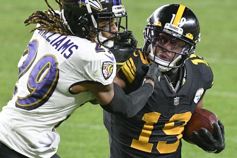 El receptor de los Steelers de Pittsburgh JuJu Smith-Schuster intenta quitarse de encima al cornerback de los Ravens de Baltimore Tramon Williams.