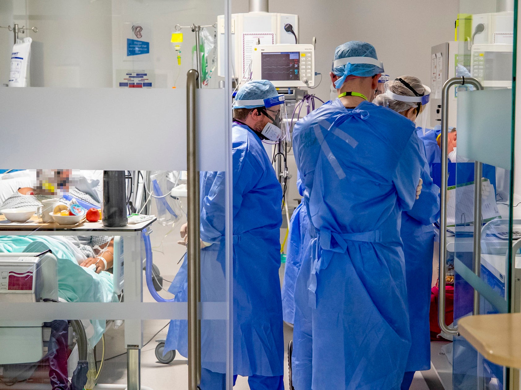 Los trabajadores de la salud que usan equipo de protección personal completo (EPP) atienden a un paciente en la unidad de cuidados intensivos (UCI) del Hospital Whiston en Merseyside