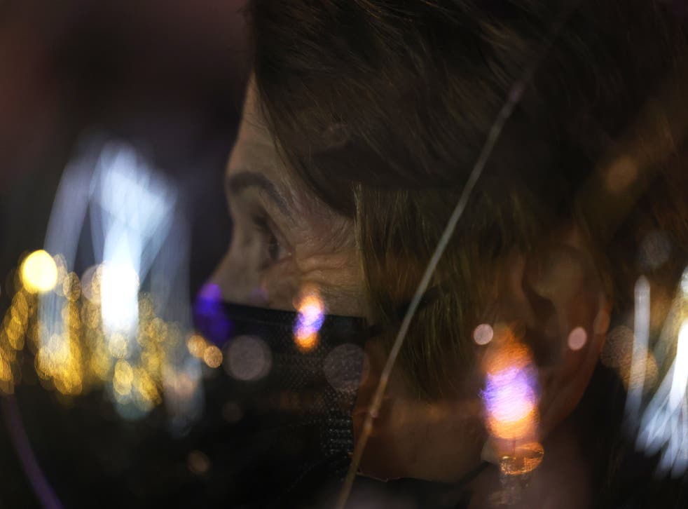 NUEVA YORK, NUEVA YORK - 10 DE DICIEMBRE: Una mujer observa cómo el rabino Shmuel Butman habla a la multitud antes de encender la primera vela de una menorá en la primera noche de Jánuca en la calle 59 de Manhattan el 10 de diciembre de 2020 en la ciudad de Nueva York. La menorá más grande del mundo, patrocinada por la Organización Juvenil de Lubavitch y diseñada por el artista Yaakov Agam, es un símbolo de la festividad de Janucá. La menorá de este año también honra a los neoyorquinos que han fallecido debido a COVID-19. 