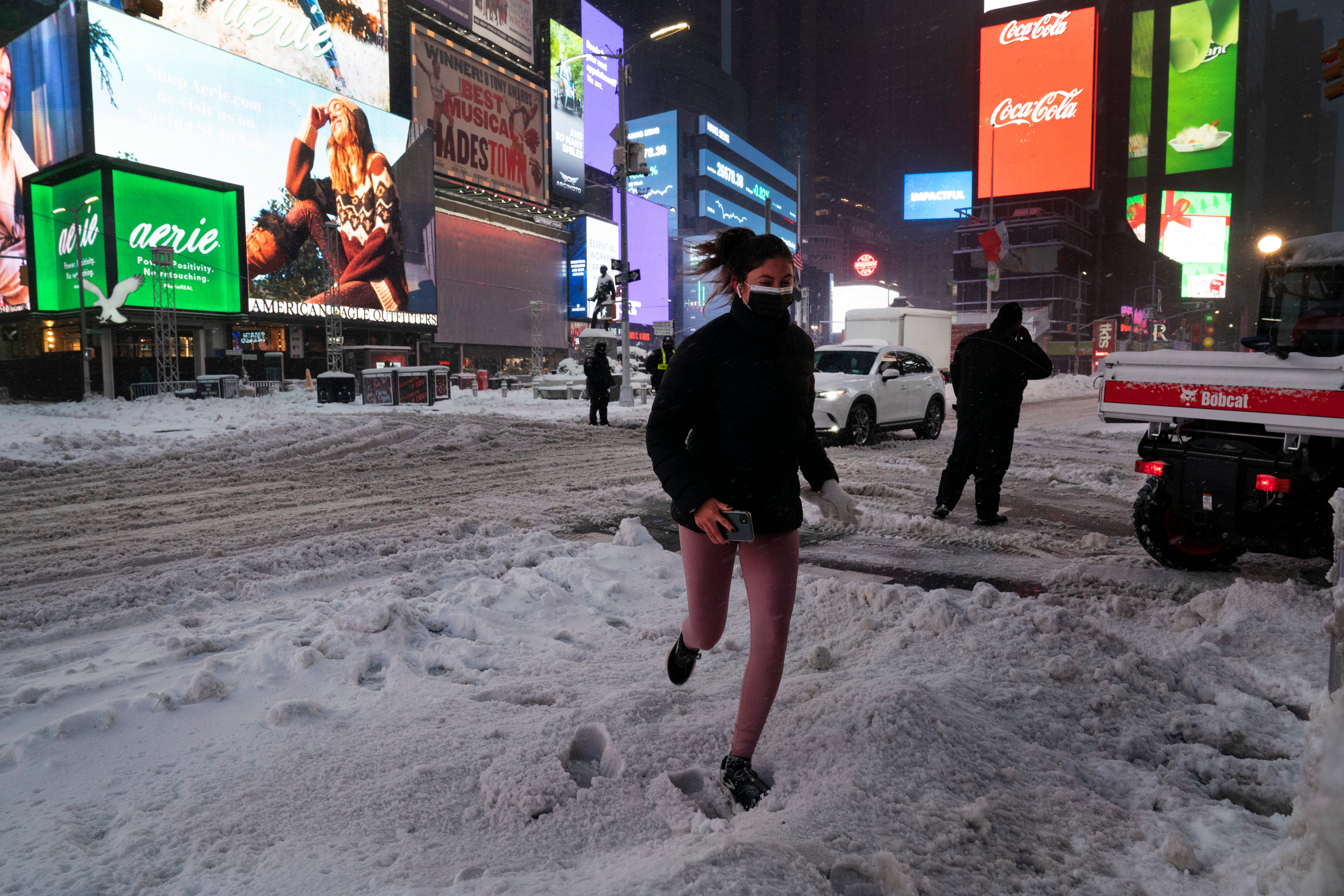 <p>Una mujer trota durante una nevada la noche del jueves 17 de diciembre de 2020, en Times Square, en la ciudad de Nueva York.&nbsp;</p>