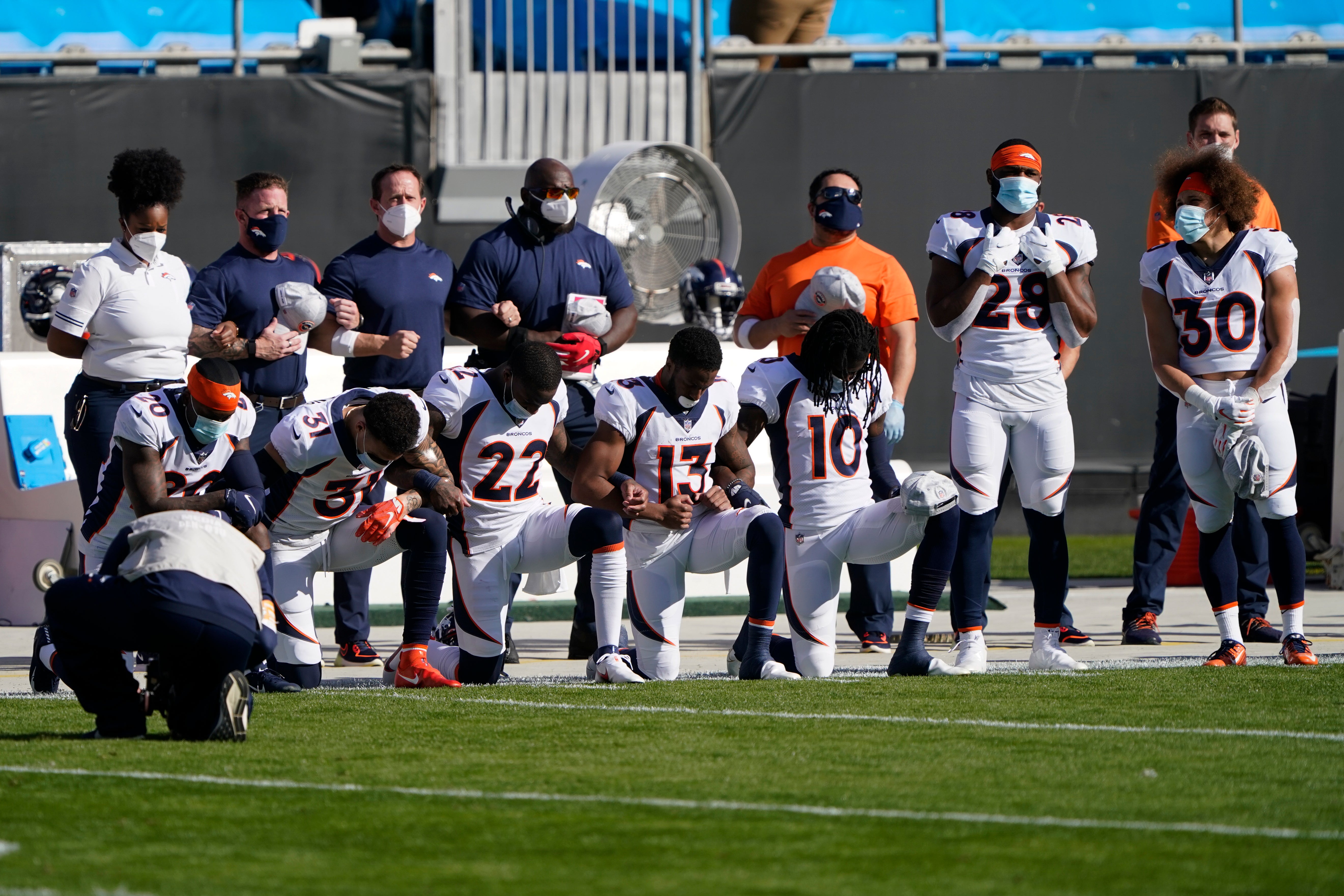 Miembros de los Broncos de Denver escuchan arrodillados el himno nacional antes del partido de NFL contra los Panthers de Carolina, el domingo 13 de diciembre de 2020, en Charlotte, Carolina del Norte.&nbsp;