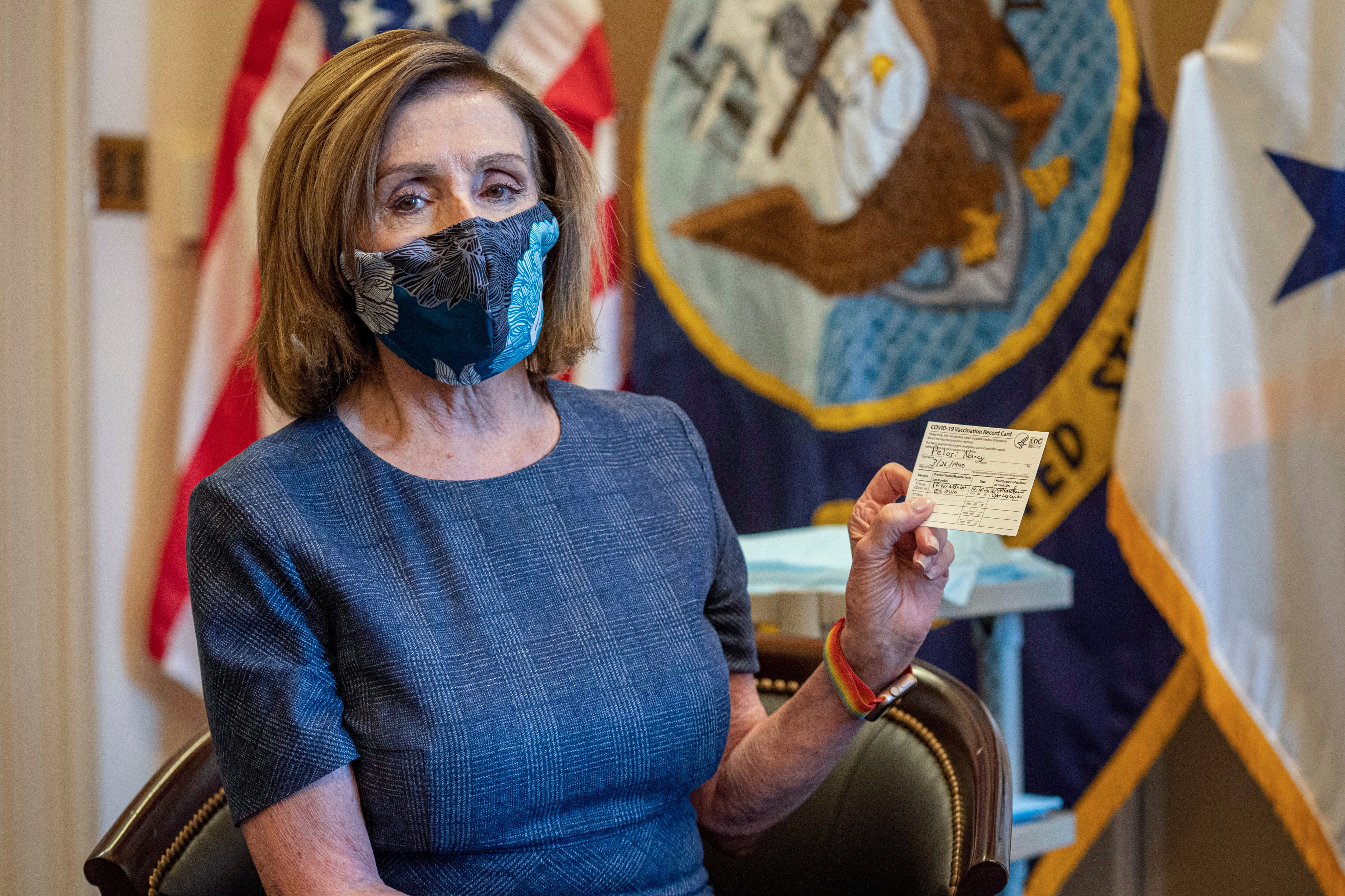 La presidenta de la Cámara de Representantes, la demócrata Nancy Pelosi, sostiene un certificado de vacunación contra el COVID-19.&nbsp;