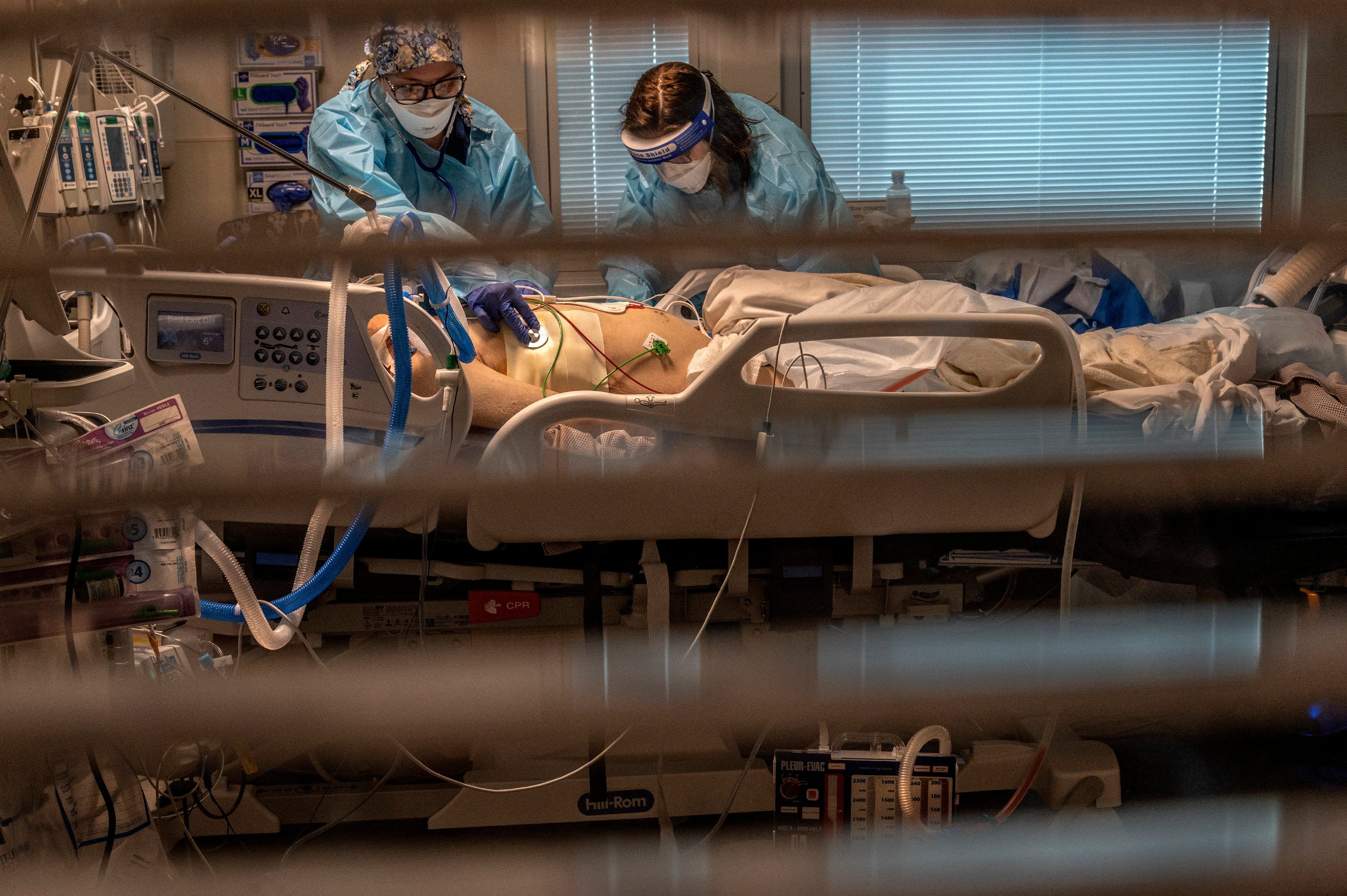 <p>La asistente de aboratorio de flebotomías Jennifer Cukati, a la derecha, y la enfermera Carina Klescewski, a la izquierda, atienden a un paciente de COVID-19 en la UCI del Centro Médico Sutter Roseville Medical Center en Roseville, California, el martes 22 de diciembre de 2020. &nbsp;</p>