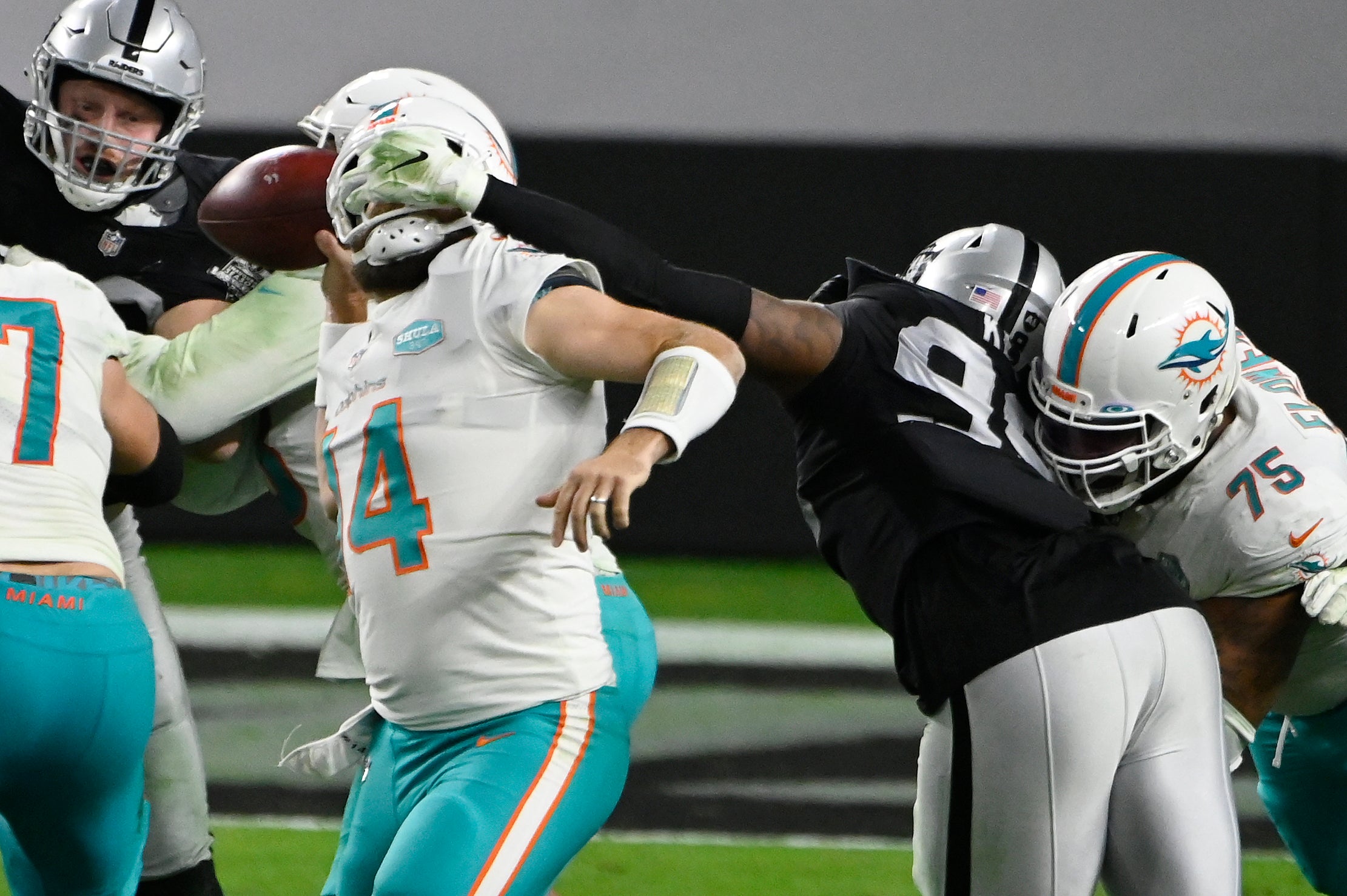 Ryan Fitzpatrick, quarterback de los Dolphins de Miami, es sujetado de la máscara por Arden Key, de los Raiders de Las Vegas, en el encuentro del sábado 26 de diciembre de 2020.
