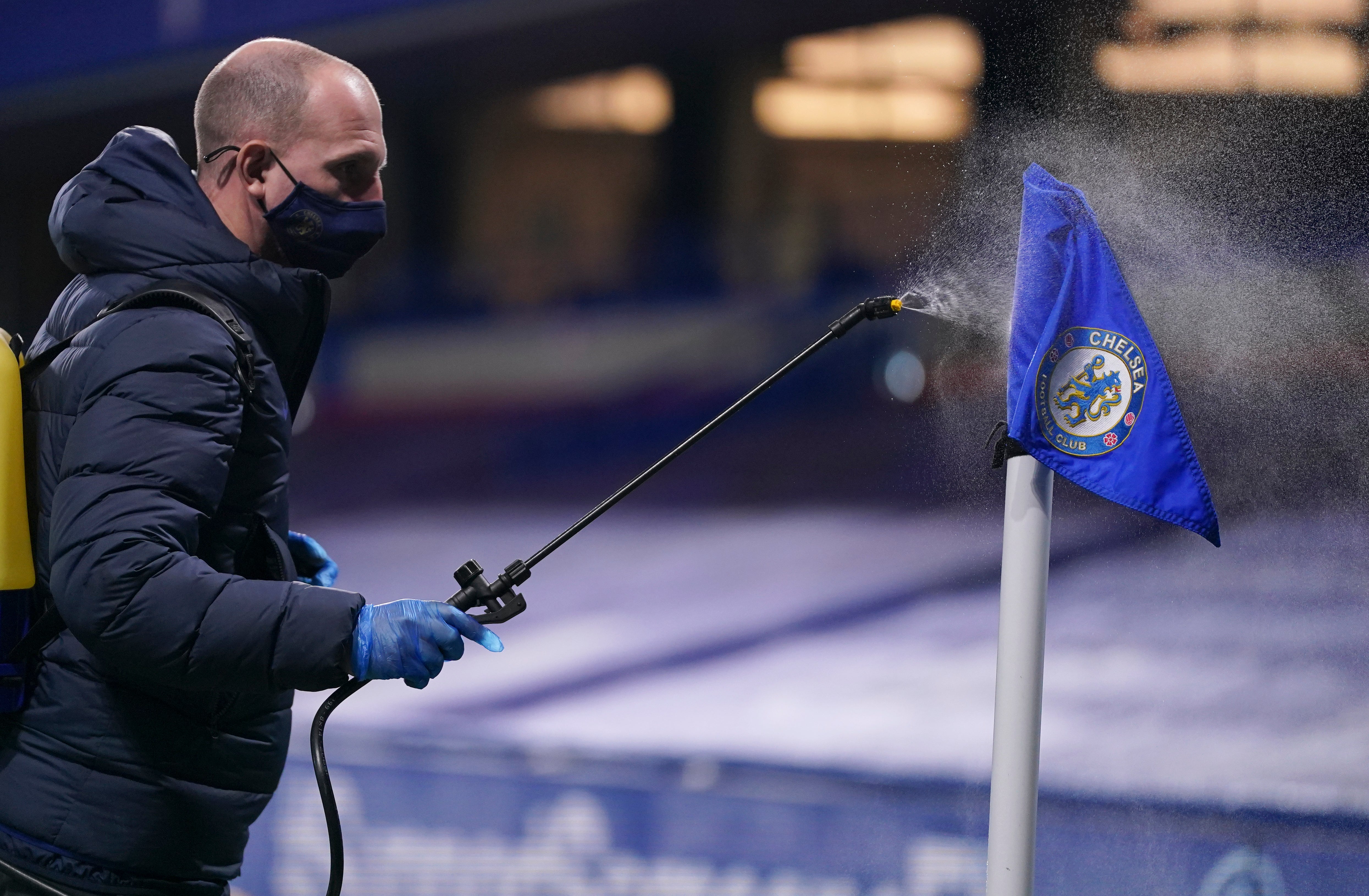 Un encargado rocía desinfectante sobre una bandera de esquina durante una pausa en un partido de la Liga Premier inglesa entre Chelsea y West Ham.
