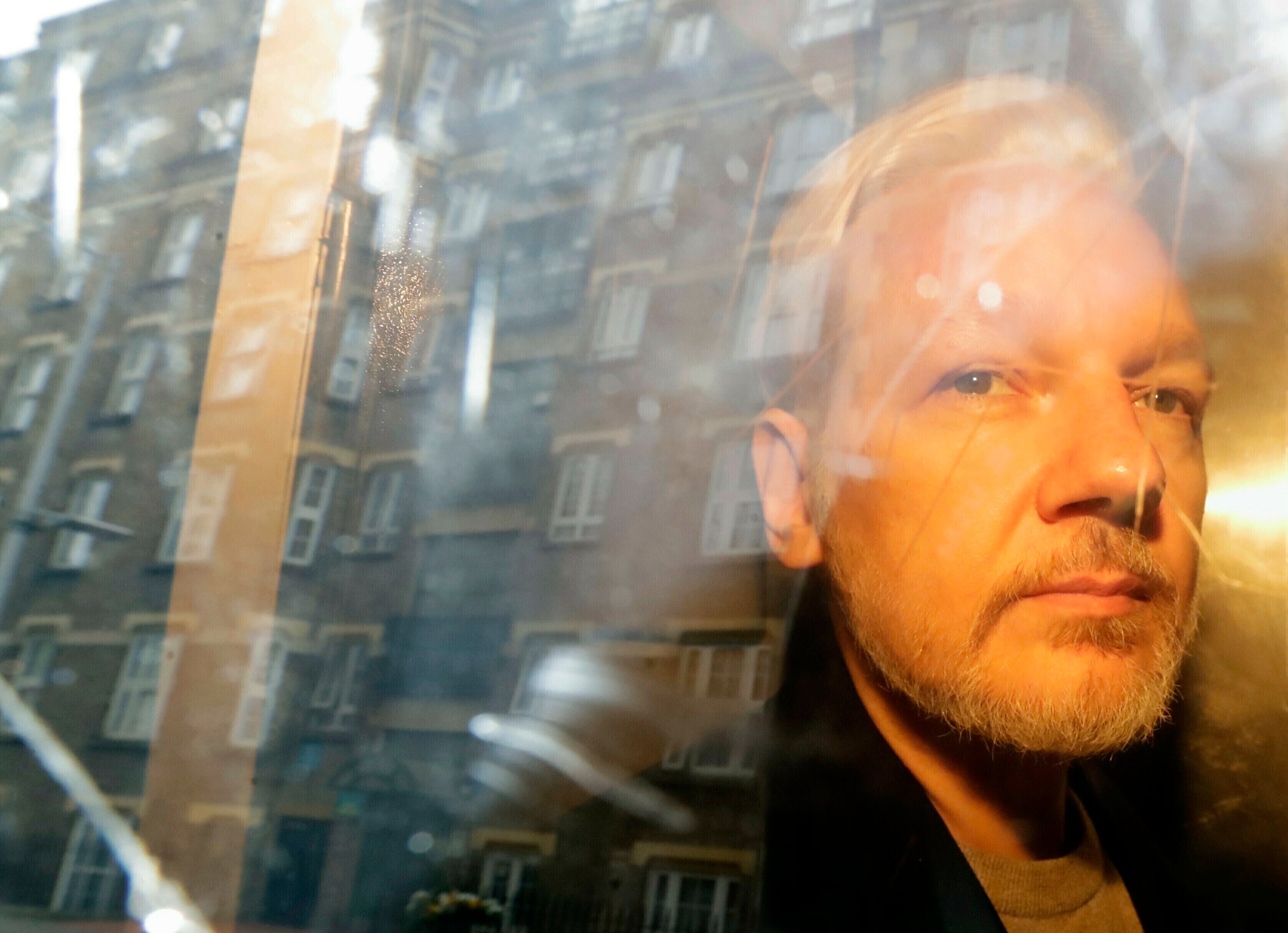 ARCHIVO - En esta fotografía del miércoles 1 de mayo de 2019 se reflejan unos edificios en la ventana mientras el fundador de WikiLeaks, Julian Assange, se aleja de la corte en la que compareció por cargos de espionaje en Londres.&nbsp;