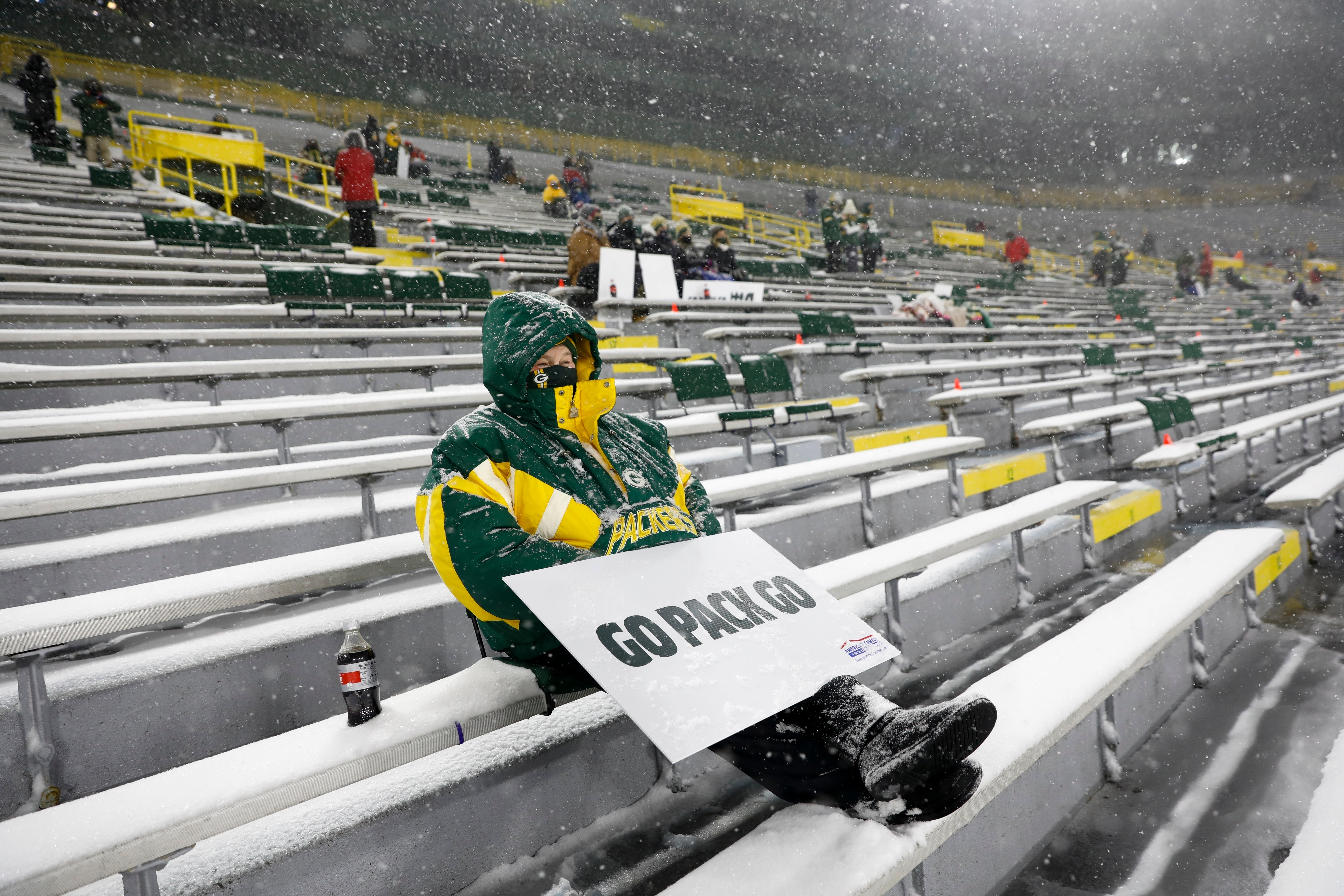 ARCHIVO - Unos cuantos fanáticos en el Lambeau Field presencian bajo una nevada el partido entre los Packers de Green Bay y los Titans de Tennessee, el domingo 27 de diciembre de 2020