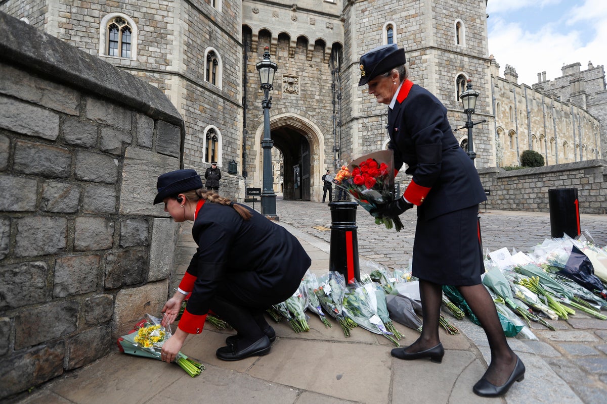 Los guardianes del Castillo de Windsor mueven flores que fueron colocadas por miembros del público