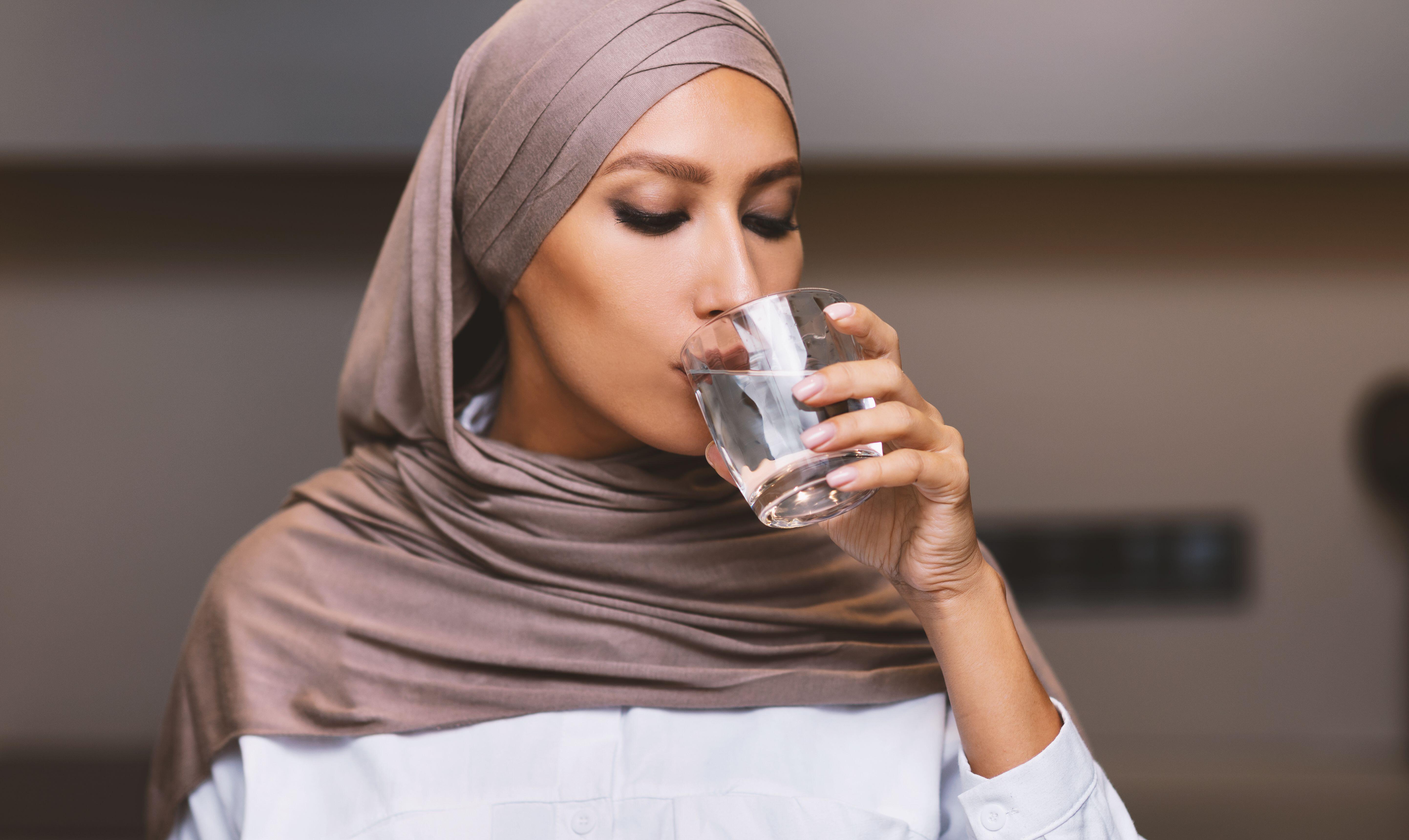 Mujer musulmana bebiendo agua
