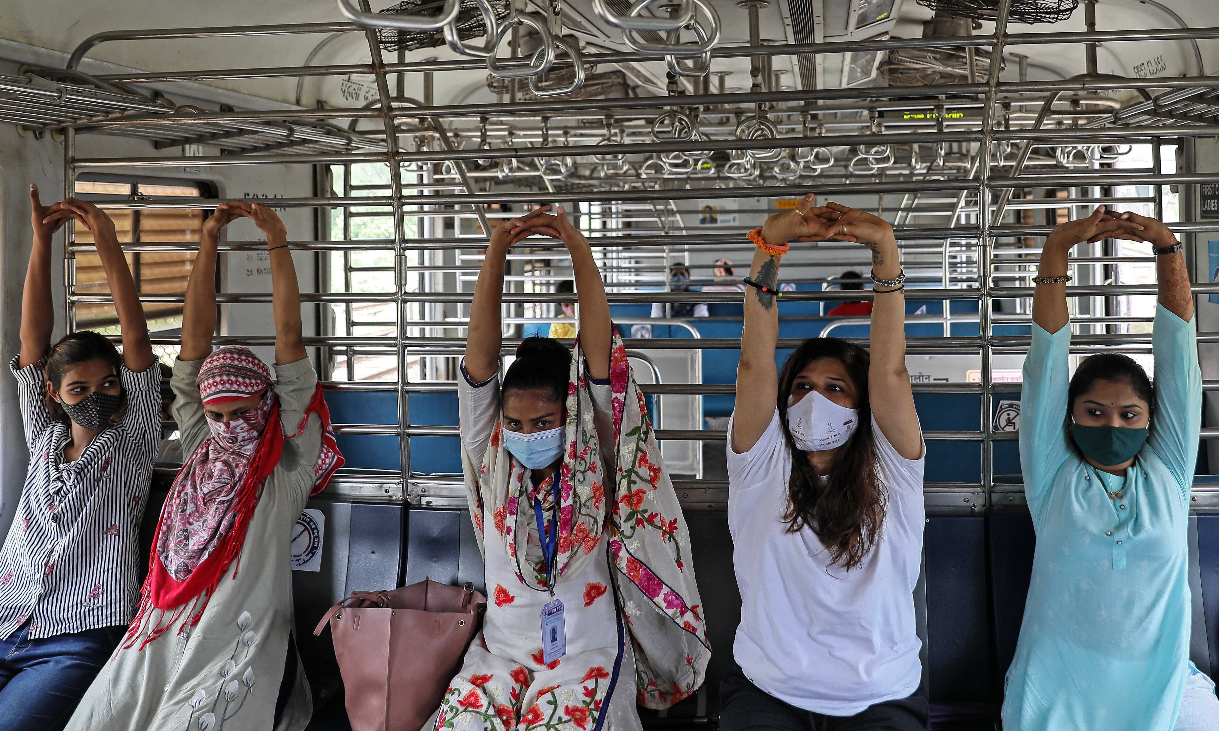 Las mujeres realizan yoga dentro de un tren local en Mumbai, India.