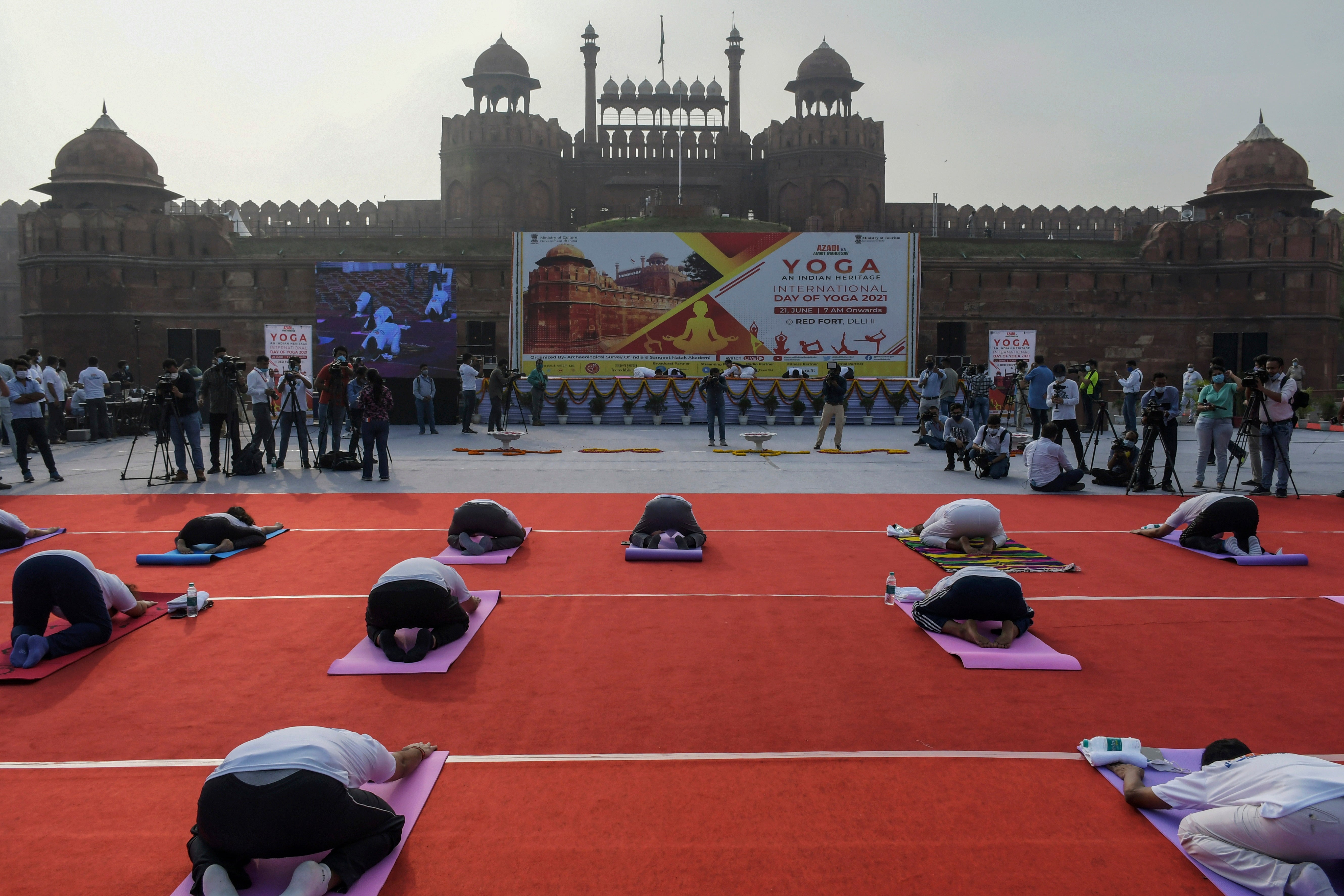 La gente practica yoga frente al monumento del Fuerte Rojo en Nueva Delhi el 21 de junio de 2021.