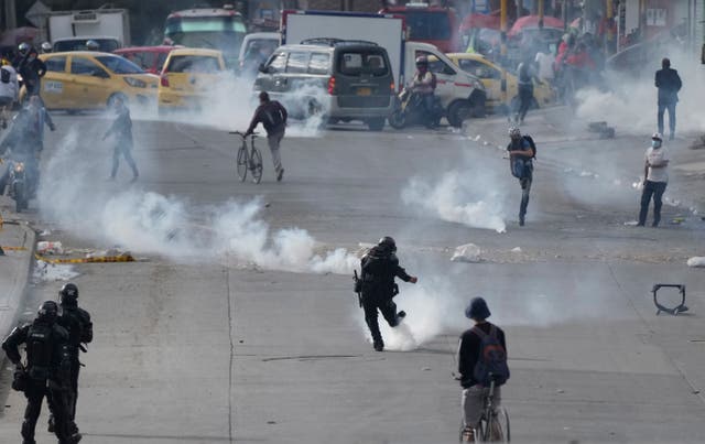 <p>Un manifestante y un policía se patean botes de gas lacrimógeno durante las continuas protestas contra el gobierno provocadas por los aumentos de impuestos propuestos sobre los servicios públicos, el combustible, los salarios y las pensiones en Bogotá, Colombia, el lunes 28 de junio de 2021.</p>