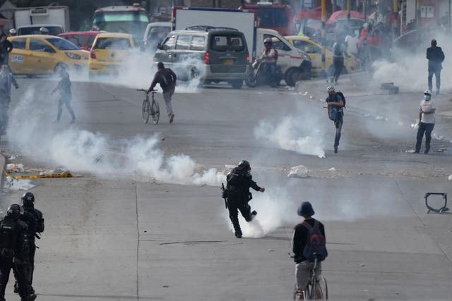 <p>Un manifestante y un policía se patean botes de gas lacrimógeno durante las continuas protestas contra el gobierno provocadas por los aumentos de impuestos propuestos sobre los servicios públicos, el combustible, los salarios y las pensiones en Bogotá, Colombia, el lunes 28 de junio de 2021.</p>