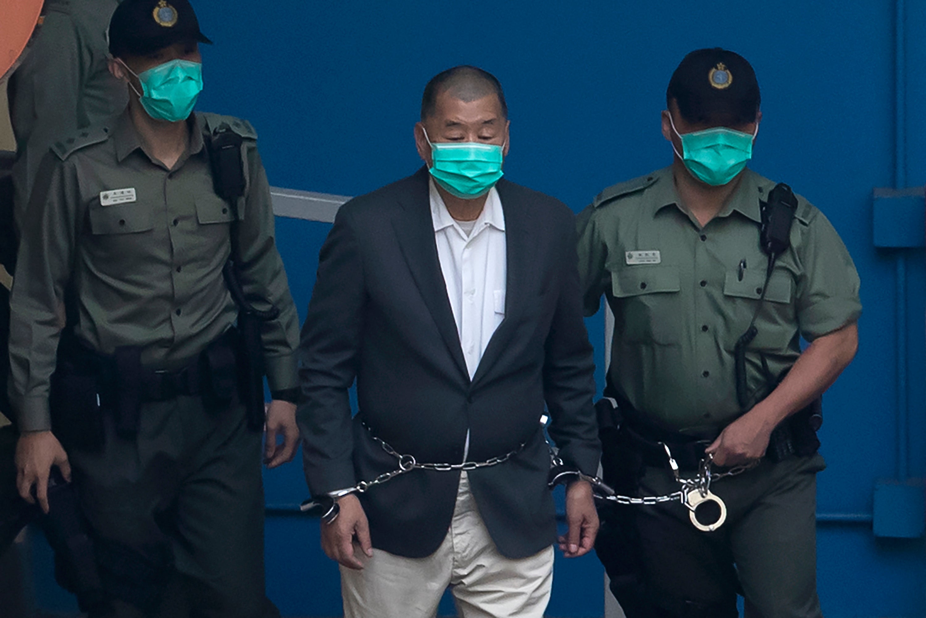 Jimmy Lai, fundador del ahora clausurado Apple Daily, es escoltado por funcionarios de los Servicios Penitenciarios hasta una camioneta antes de comparecer ante un tribunal de Hong Kong el 12 de diciembre de 2020