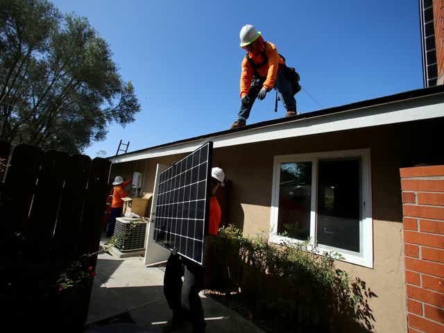 Los trabajadores levantan un panel solar sobre un techo durante una instalación solar residencial en Scripps Ranch, San Diego, California, EE. UU. 14 de octubre de 2016