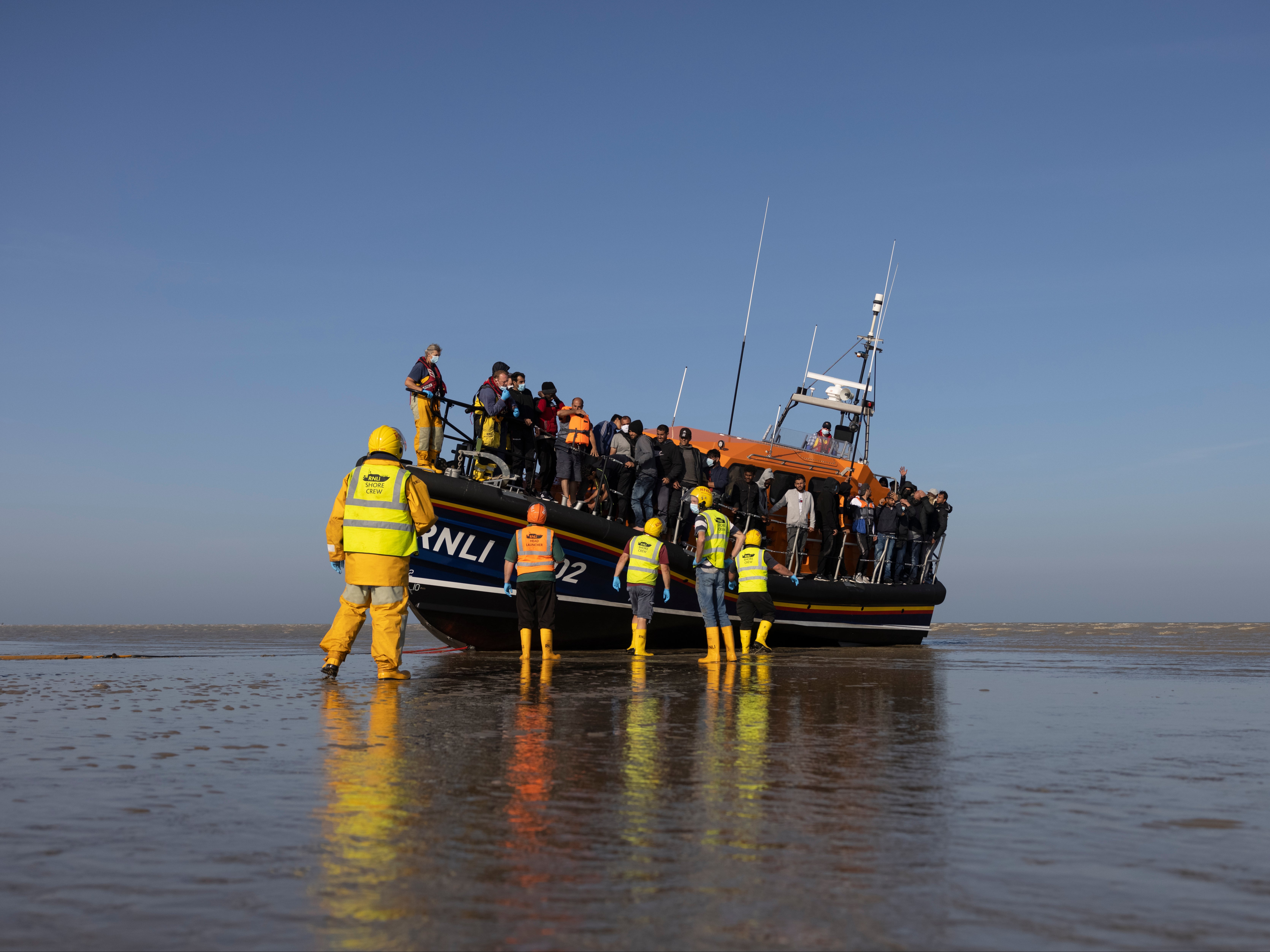 Esta foto de la semana pasada muestra a un grupo de solicitantes de asilo que llegan a la playa de Dungeness en un barco de la RNLI.