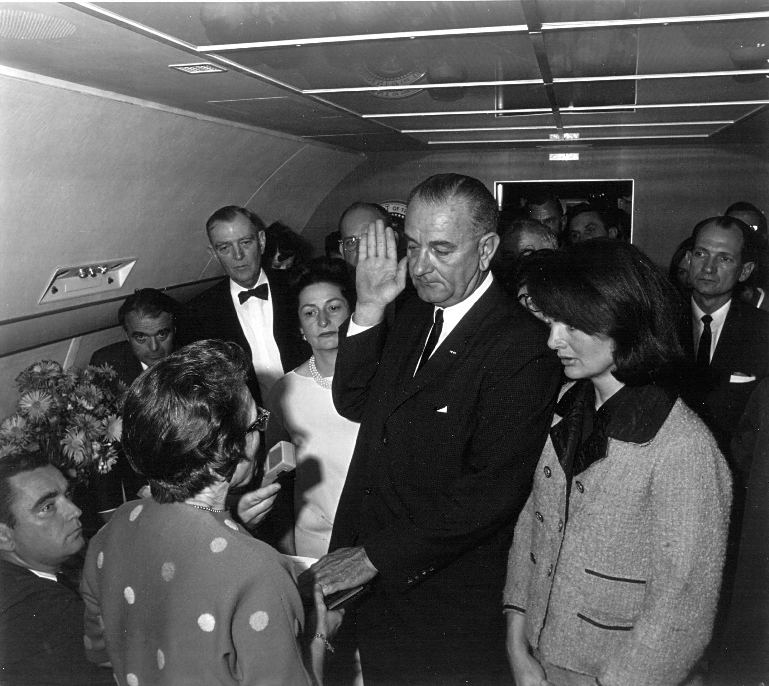 Jacqueline Kennedy (derecha) observa cómo la jueza de distrito estadounidense Sarah Hughes (segunda desde la izquierda) administra el juramento al presidente Lyndon Johnson (centro)