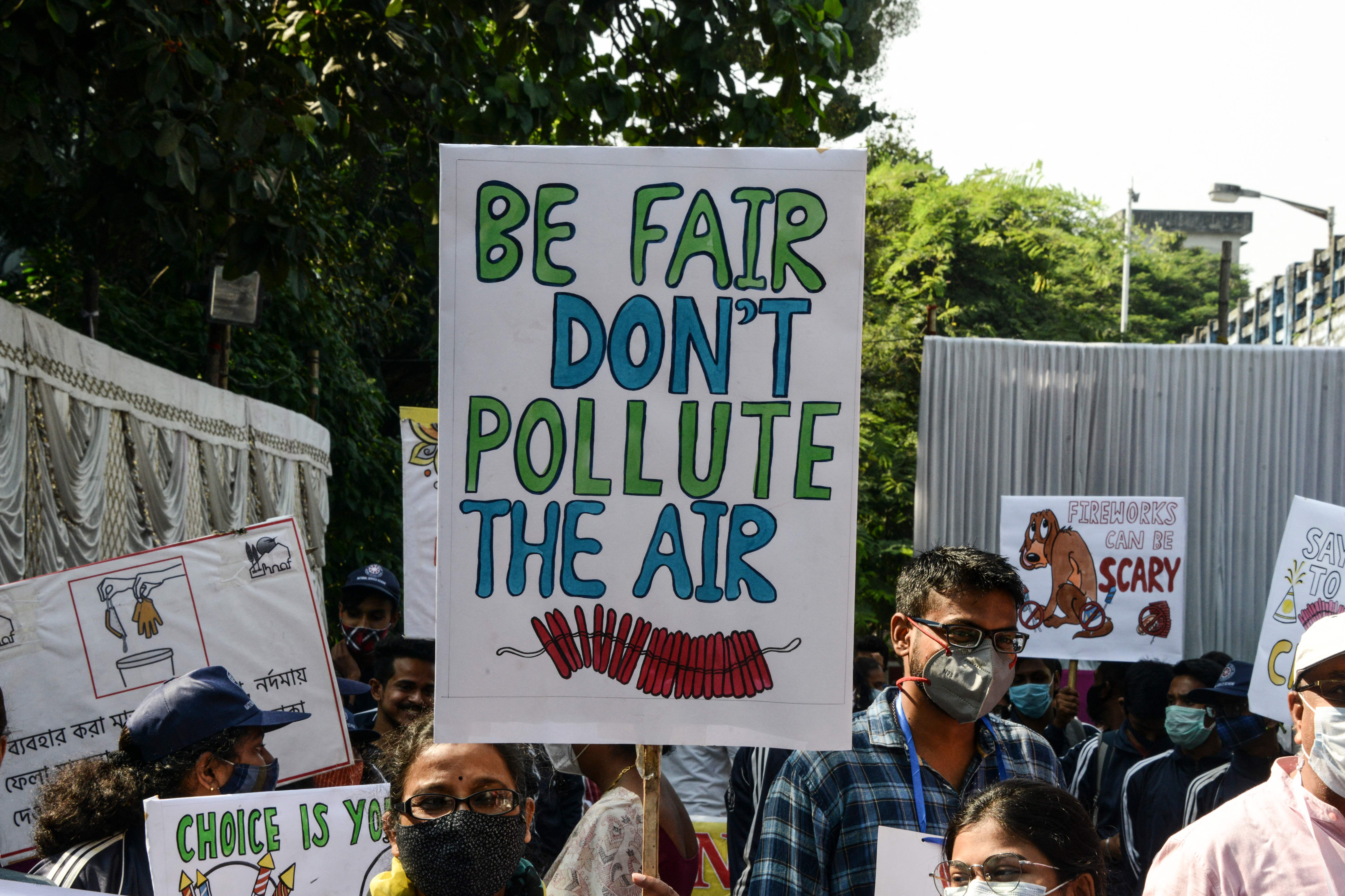 Las personas sostienen carteles para crear conciencia sobre la contaminación del aire causada por los petardos utilizados durante las celebraciones del próximo festival hindú de Diwali