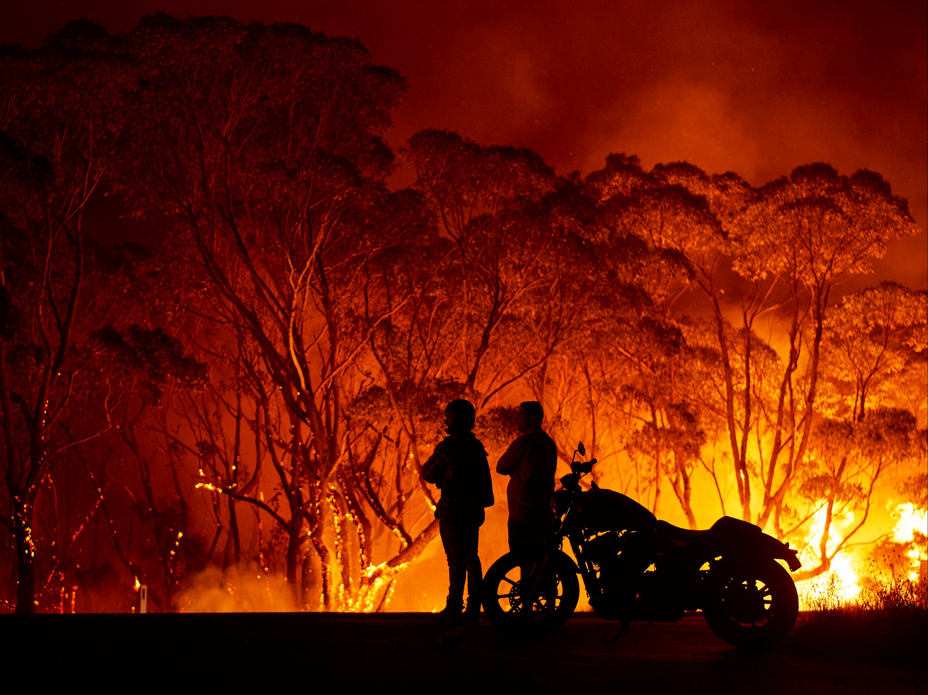 Onlookers watch flames burn through bush in Lake Tabourie, New South Wales, on 4 January 2020