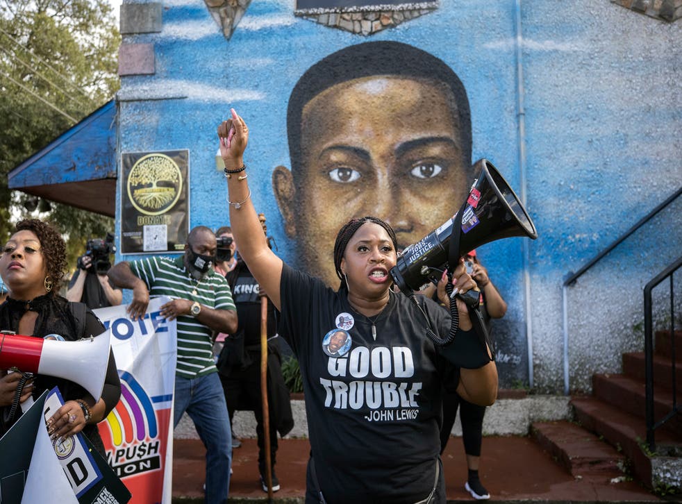 El activista de derechos civiles Porchse Miller de Atlanta grita a los partidarios de la familia de Ahmaud Arbery se reúnen frente a un mural del hombre negro durante una marcha en Brunswick, Georgia, el día 10 del juicio.