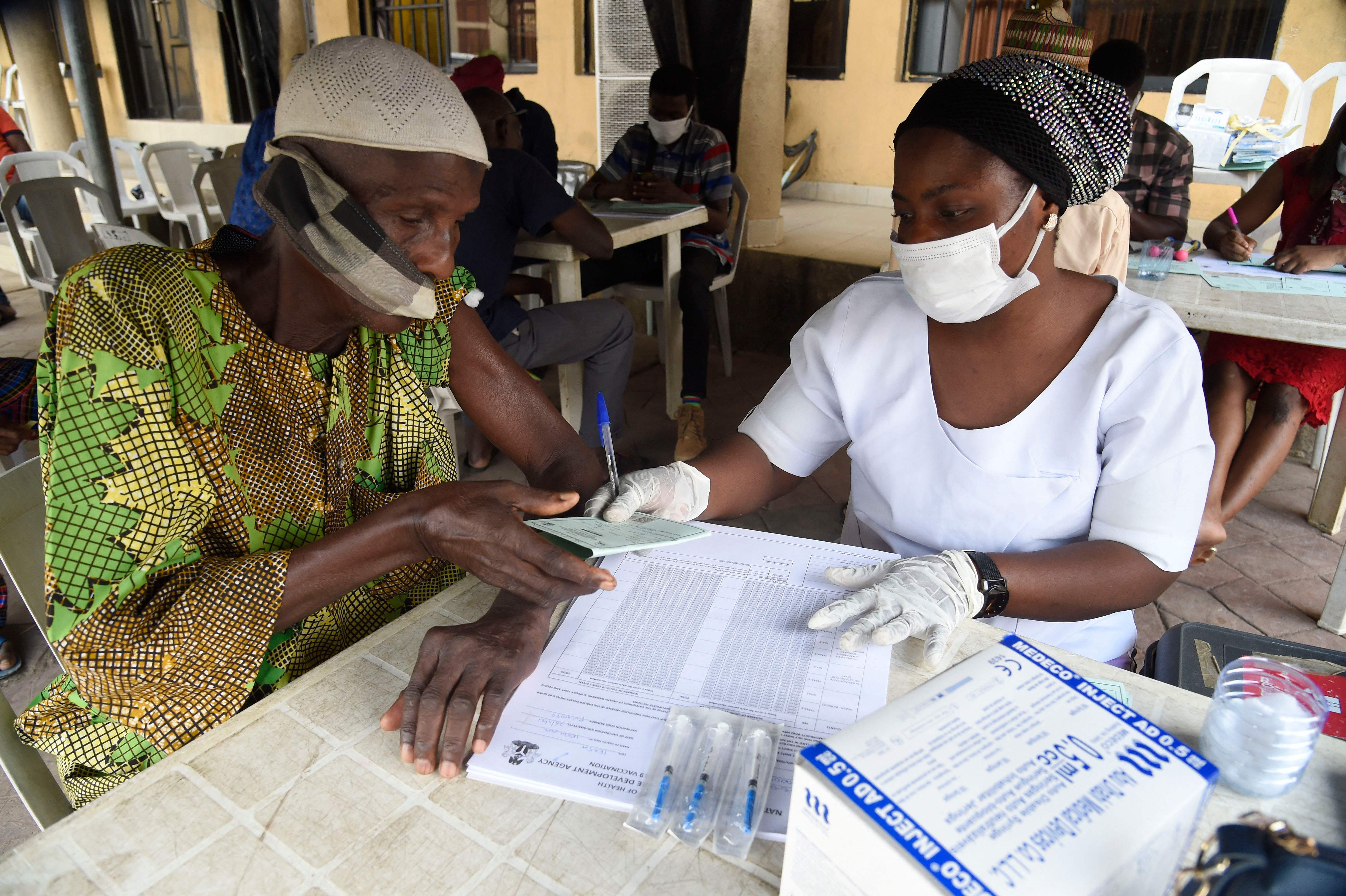 Un hombre recibe una tarjeta de vacunación de un funcionario de salud en Lagos, Nigeria