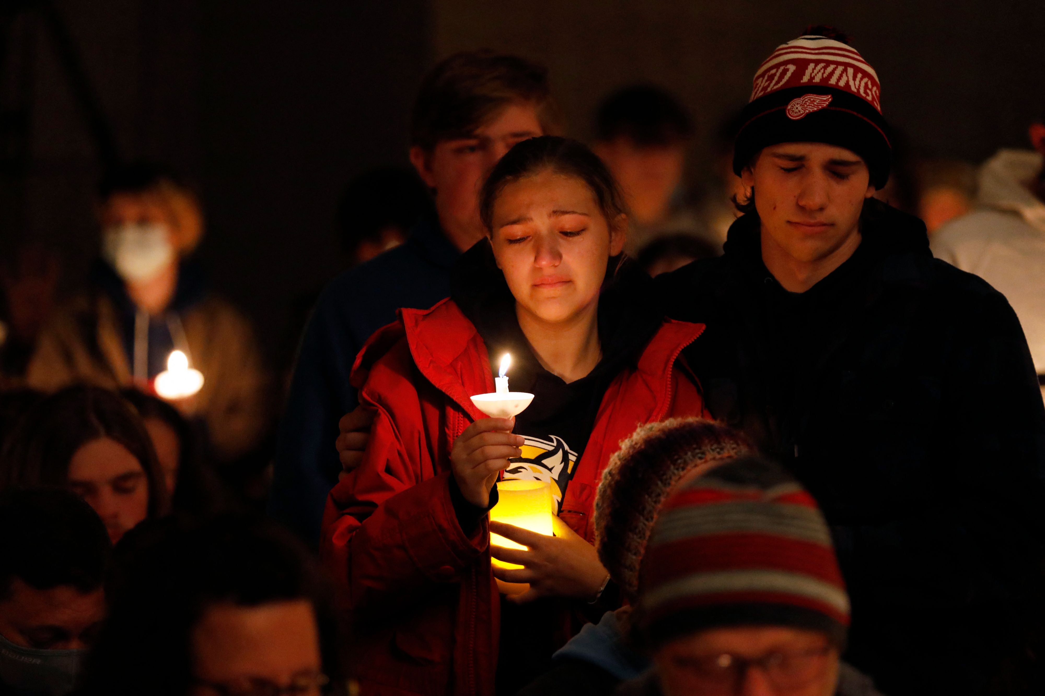 Estudiantes de Oxford High sosteniendo velas se muestran conmovidos durante una vigilia después de un tiroteo en Oxford High School en Lake Pointe Community Church en Lake Orion, Michigan