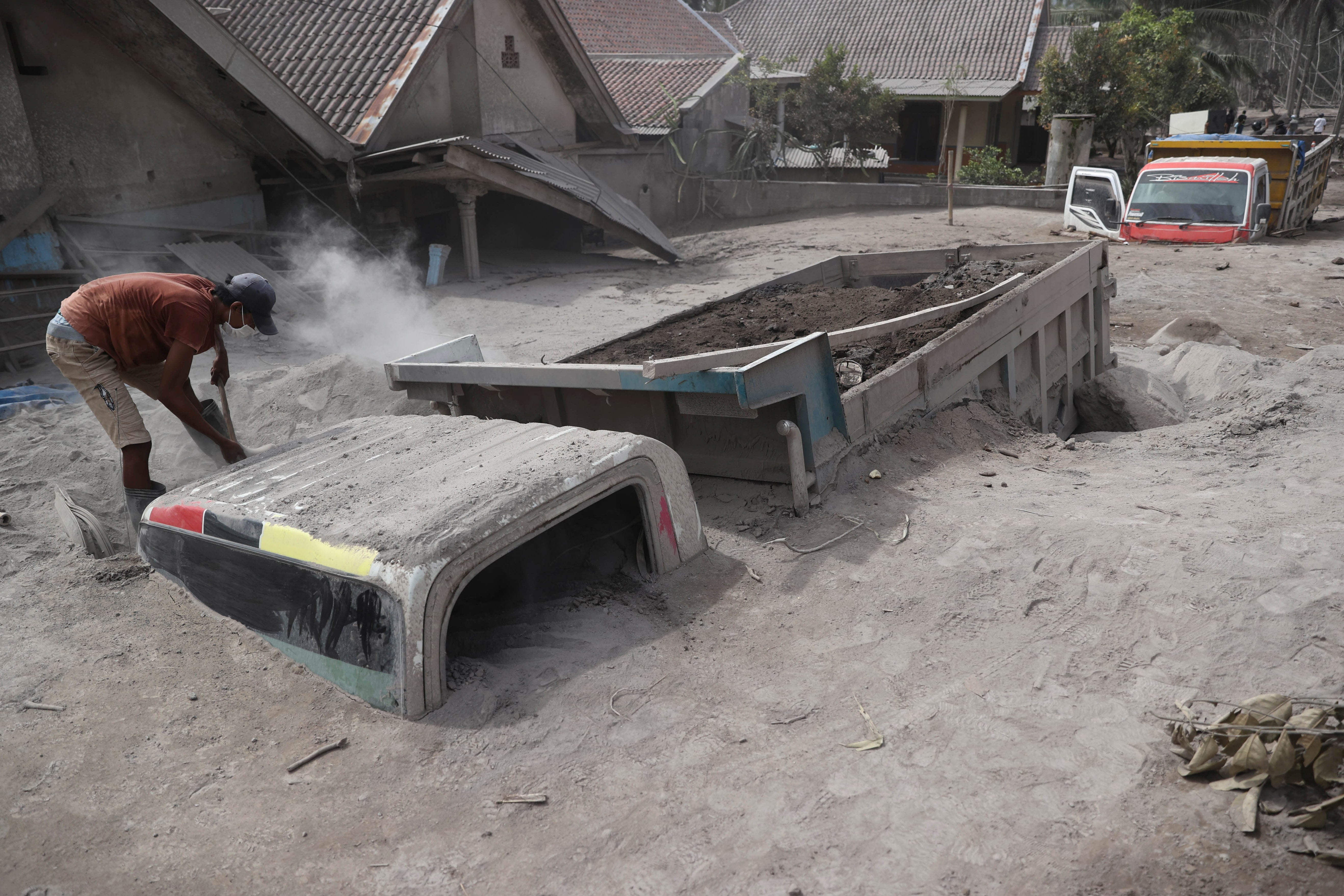 Un hombre inspecciona un camión enterrado en las cenizas tras la erupción del monte Semeru en el distrito de Lumajang, provincia de Java Oriental, Indonesia