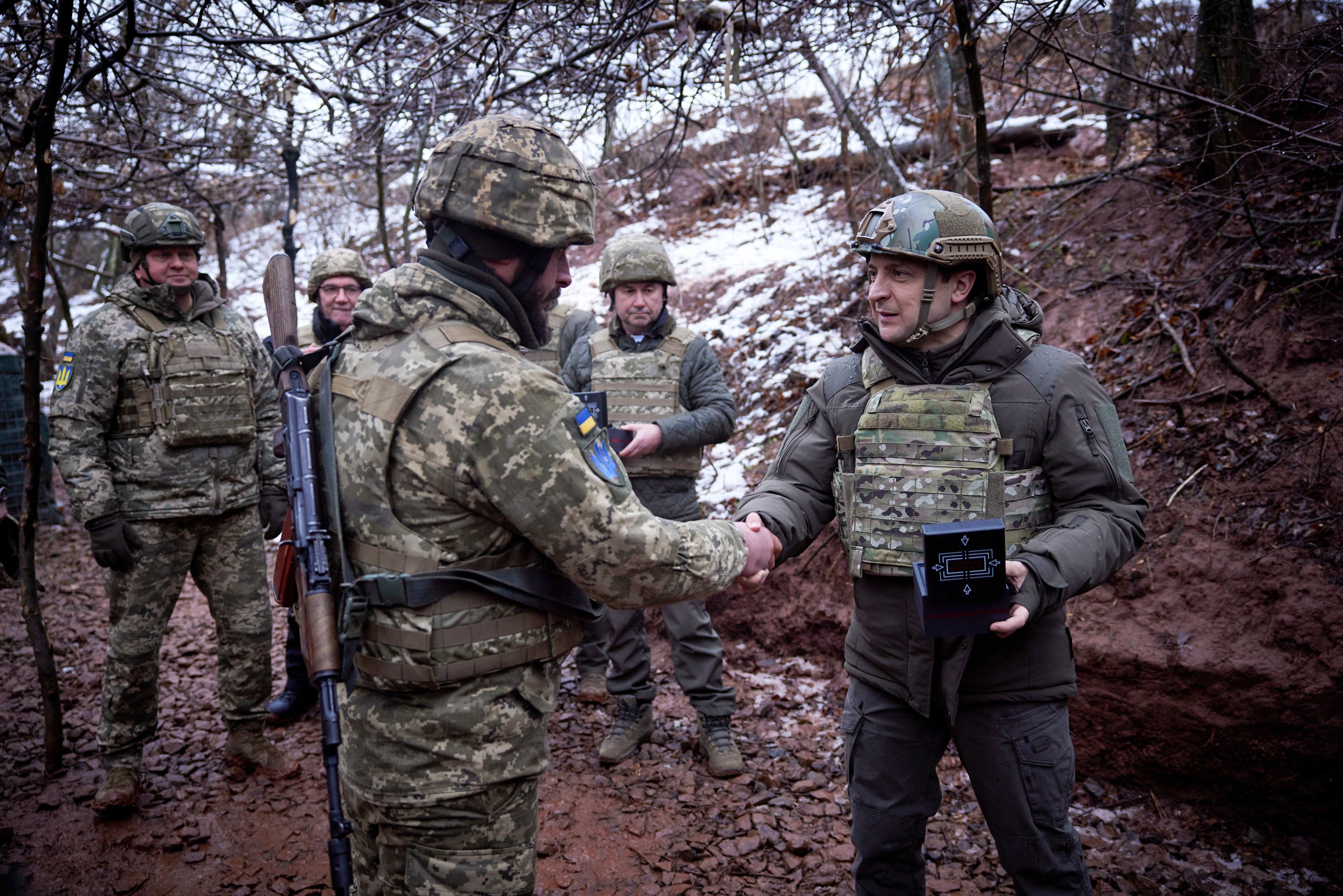 El presidente ucraniano Volodymyr Zelenskyy, a la derecha, premia a un soldado en una trinchera mientras visita la región de Donetsk, en el este de Ucrania, golpeada por la guerra, el lunes 6 de diciembre de 2021. (Oficina de Prensa de la Presidencia de Ucrania vía AP)