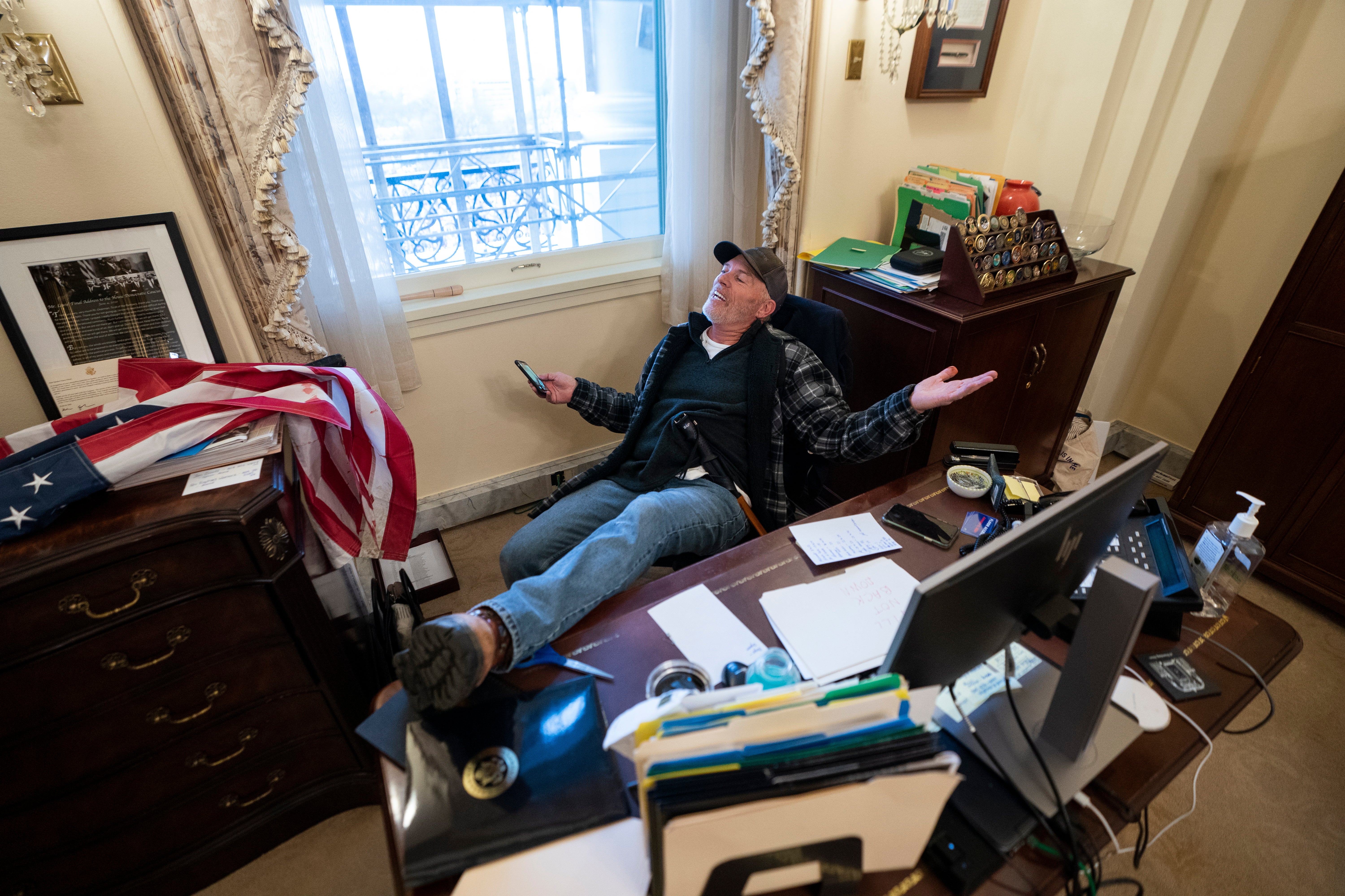 Un partidario del presidente de los EE.UU. Trump sentado en el escritorio de la Presidenta de la Cámara Pelosi, después de que los partidarios de Trump irrumpieran en el Capitolio en Washington, DC el 6 de enero del 2021